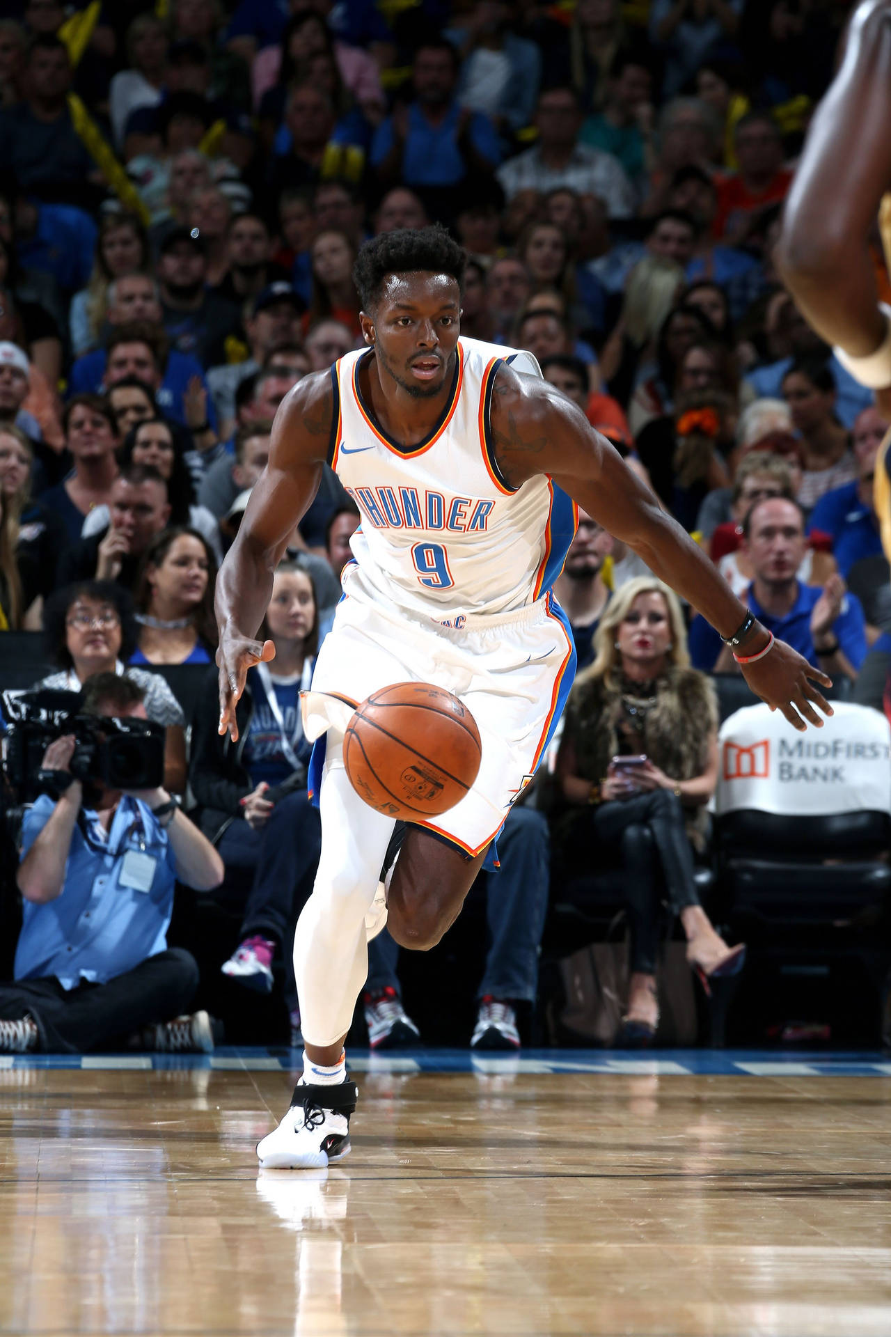 籃球運動員在比賽中運球，背景有觀眾。 — NBA 壁紙