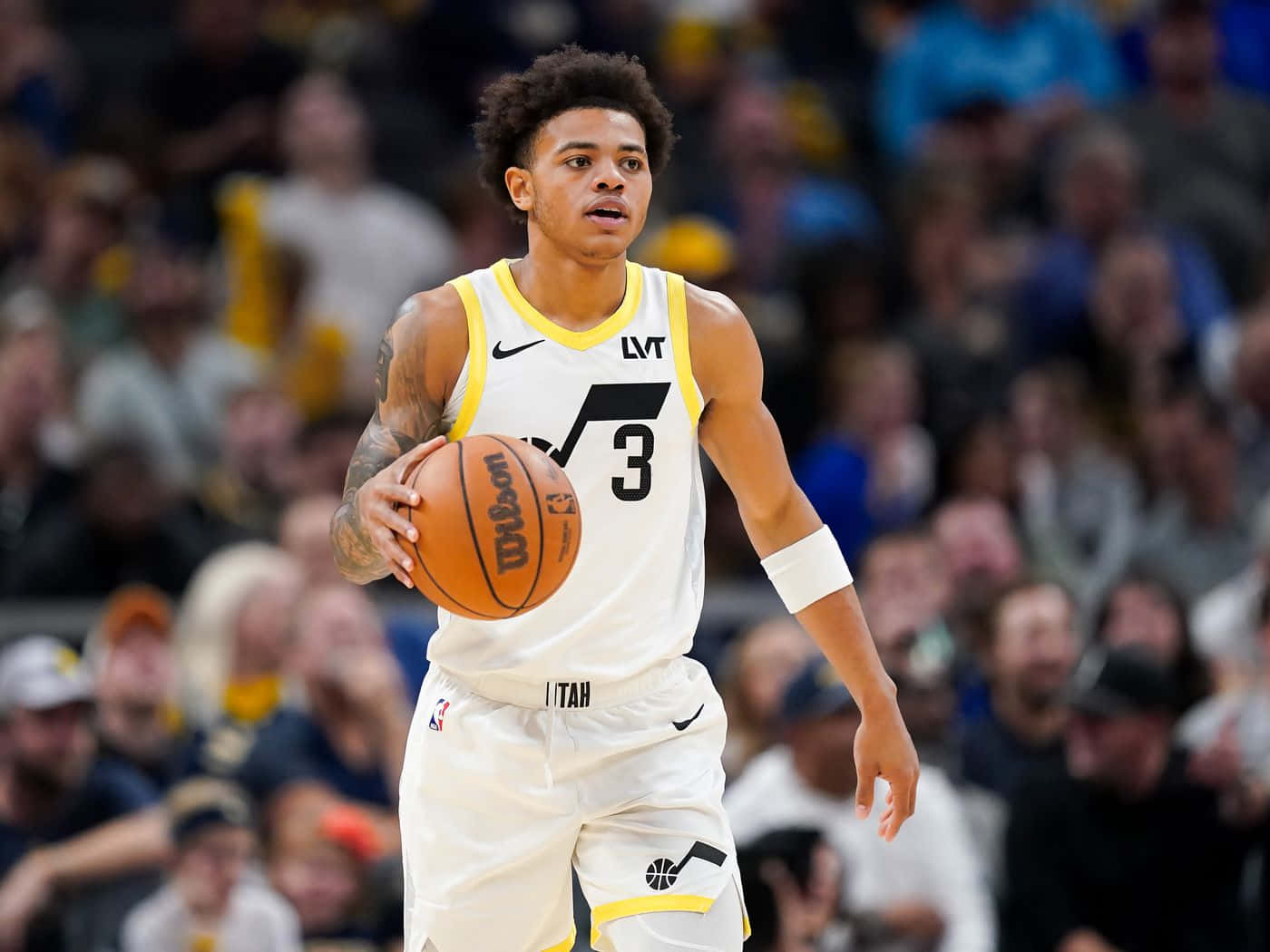 籃球運動員在比賽中運球，背景有觀眾。 — NBA 壁紙