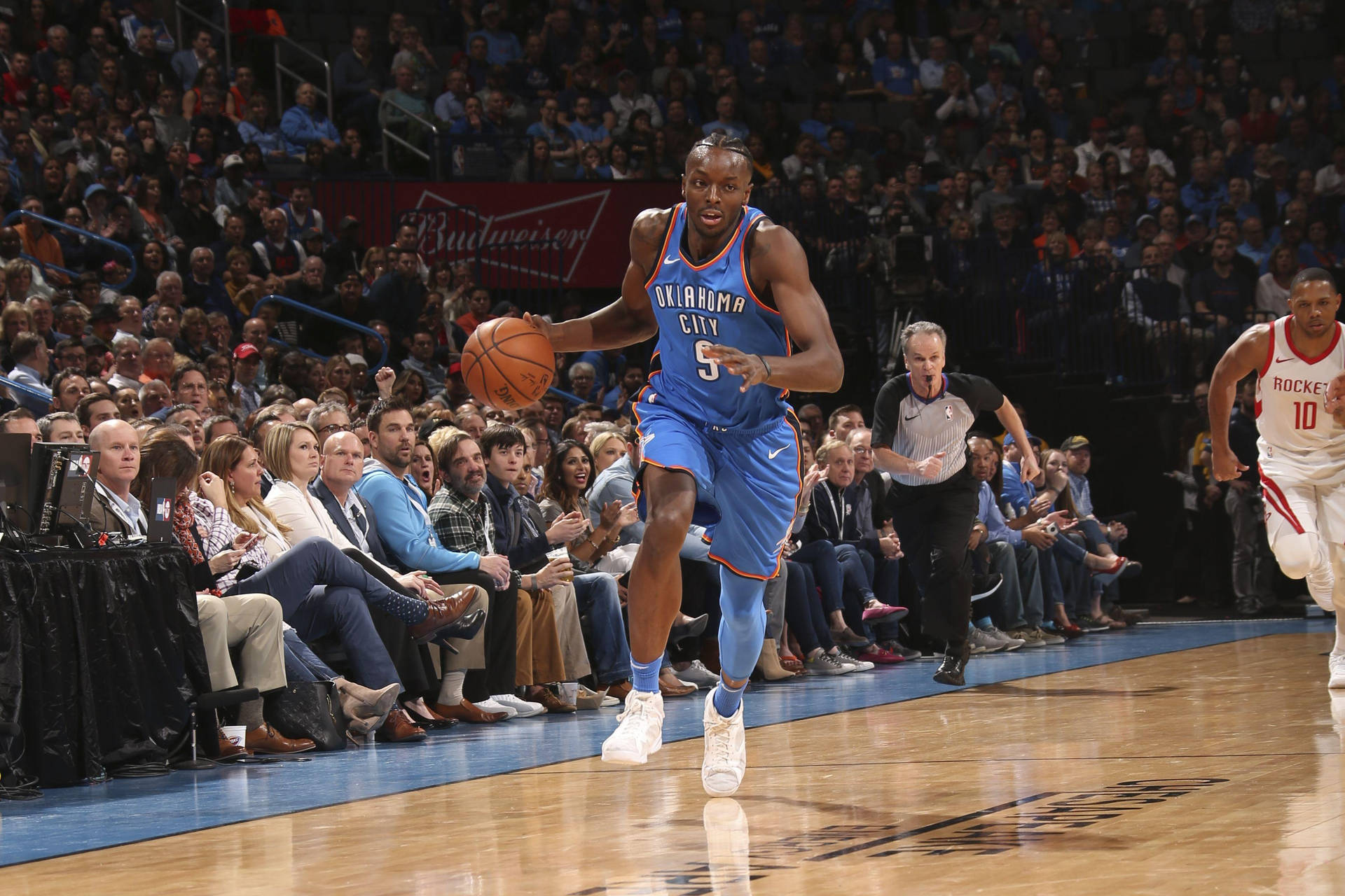 籃球運動員在職業比賽中運球，背景有觀眾。 — NBA 壁紙