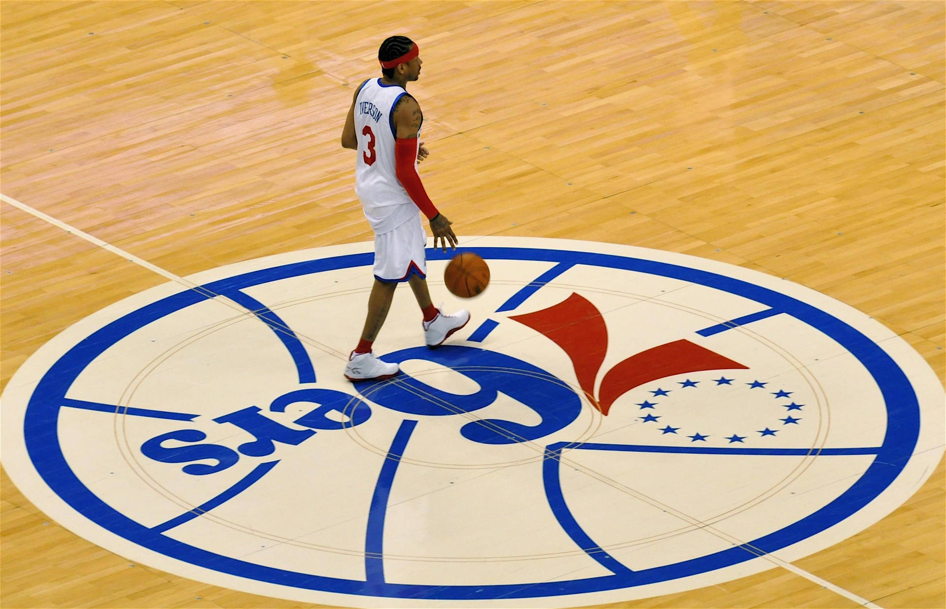 籃球運動員在木地板中圈標誌附近運球。 — NBA 壁紙