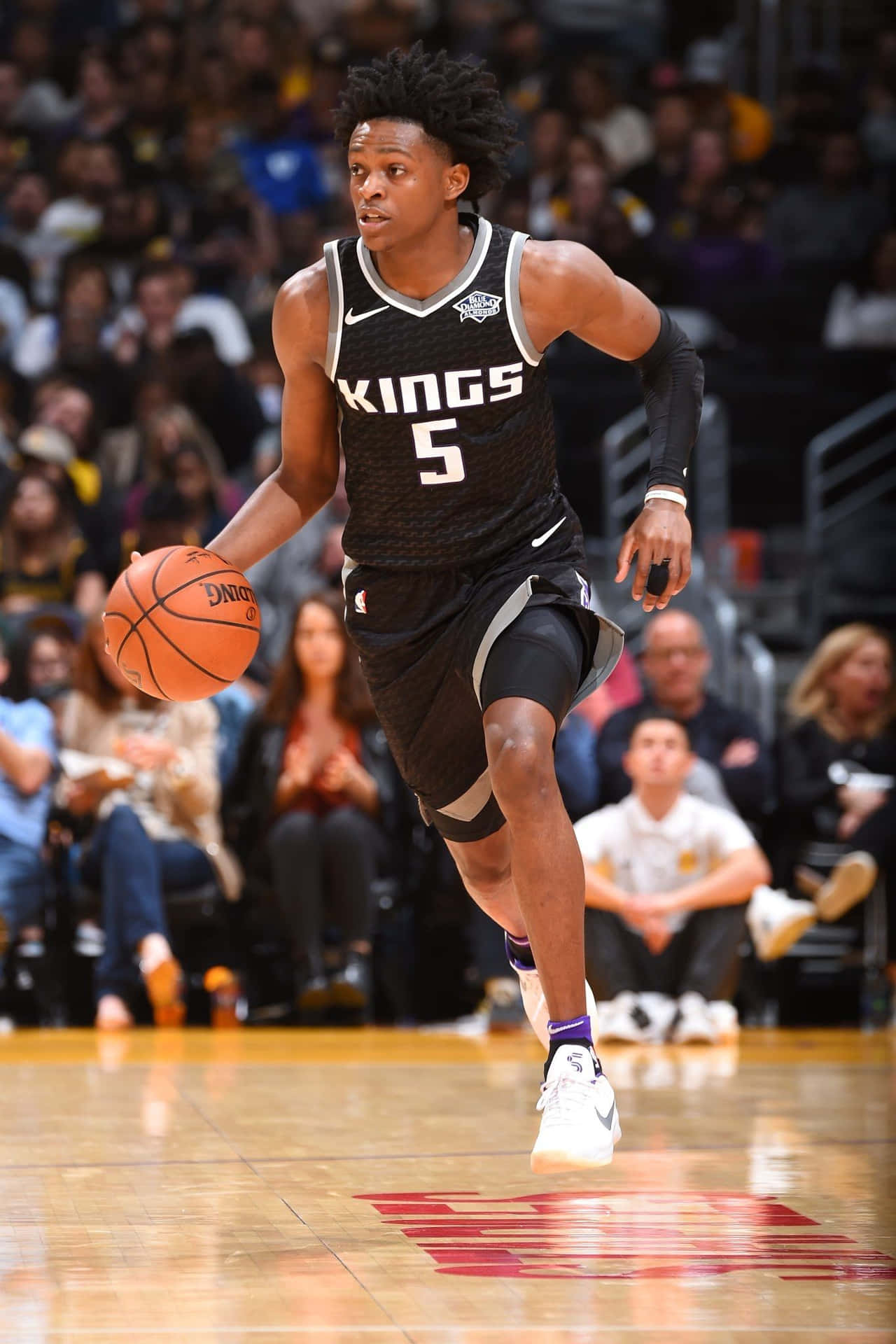 籃球運動員在比賽中運球，背景有群眾。 — NBA 壁紙