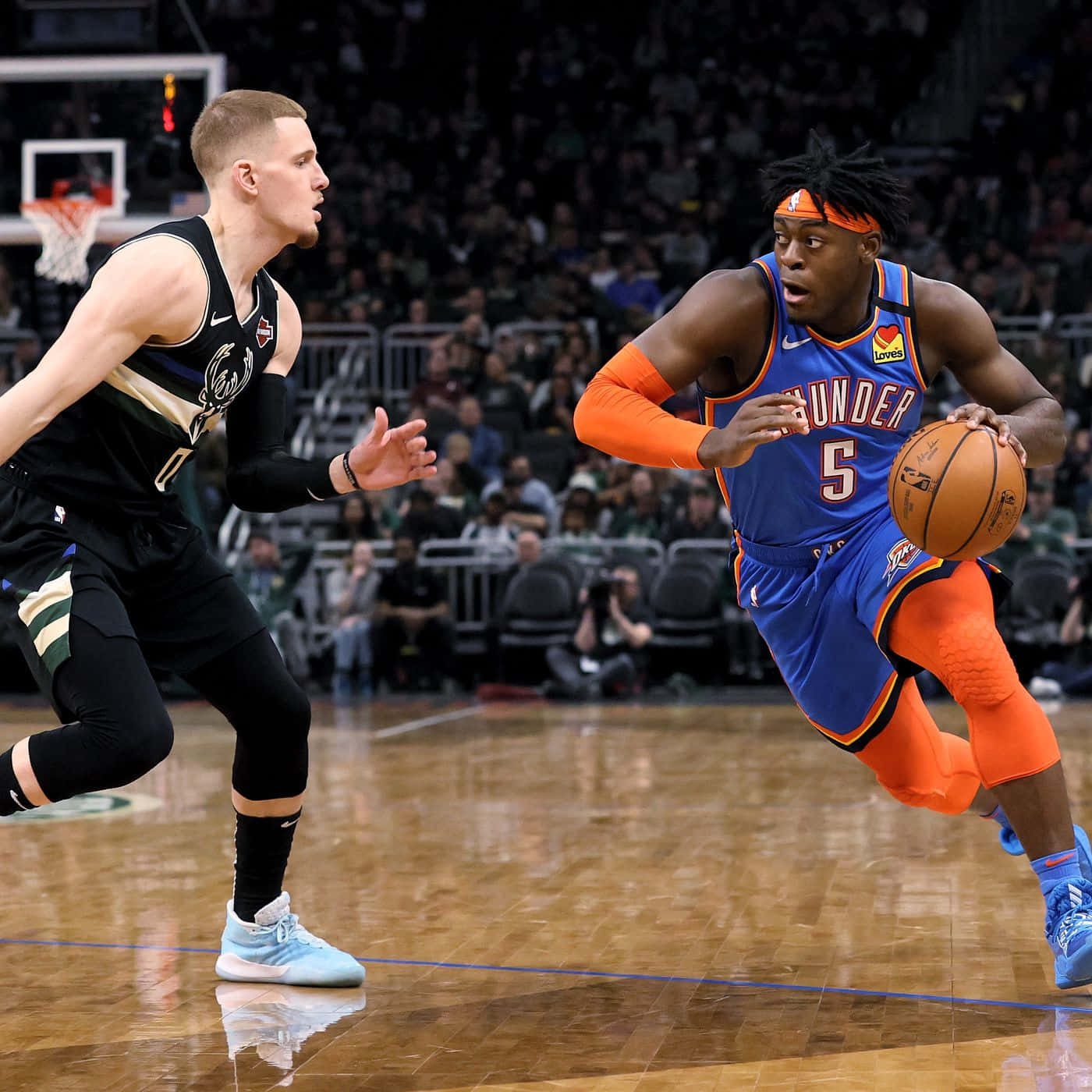 身穿藍橙色的籃球運動員在比賽中運球越過黑色防守球員。 — NBA 壁紙