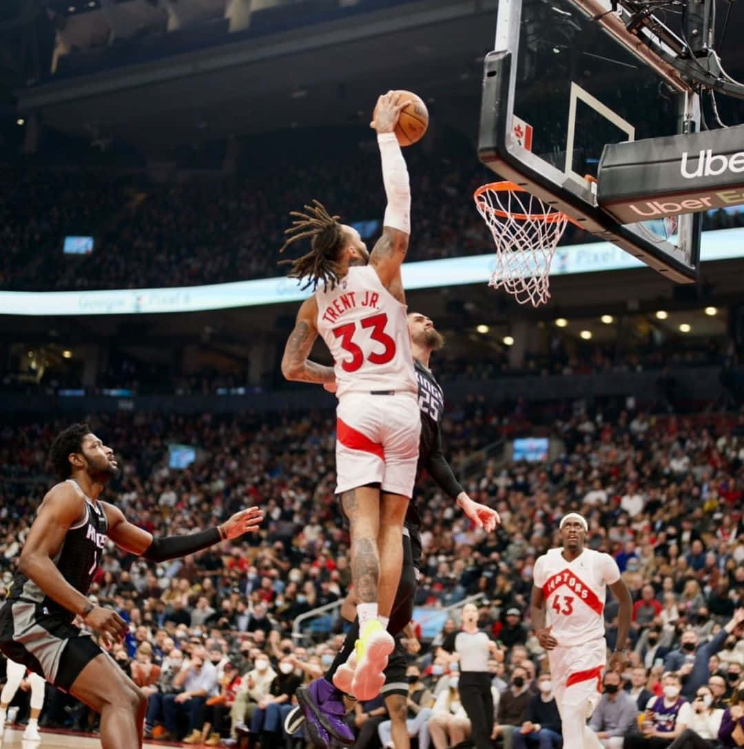 籃球運動員在空中越過防守球員灌籃，場館內座無虛席。 — NBA 壁紙