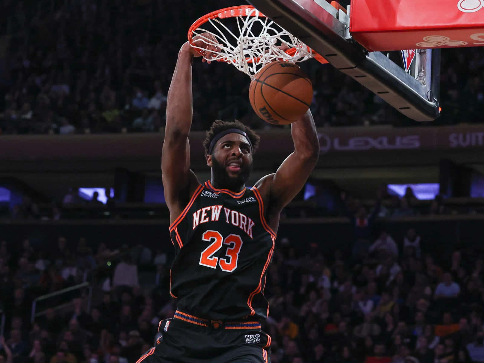 籃球運動員在擠滿觀眾的場館中灌籃，身穿紐約尼克隊球衣。 — NBA 壁紙