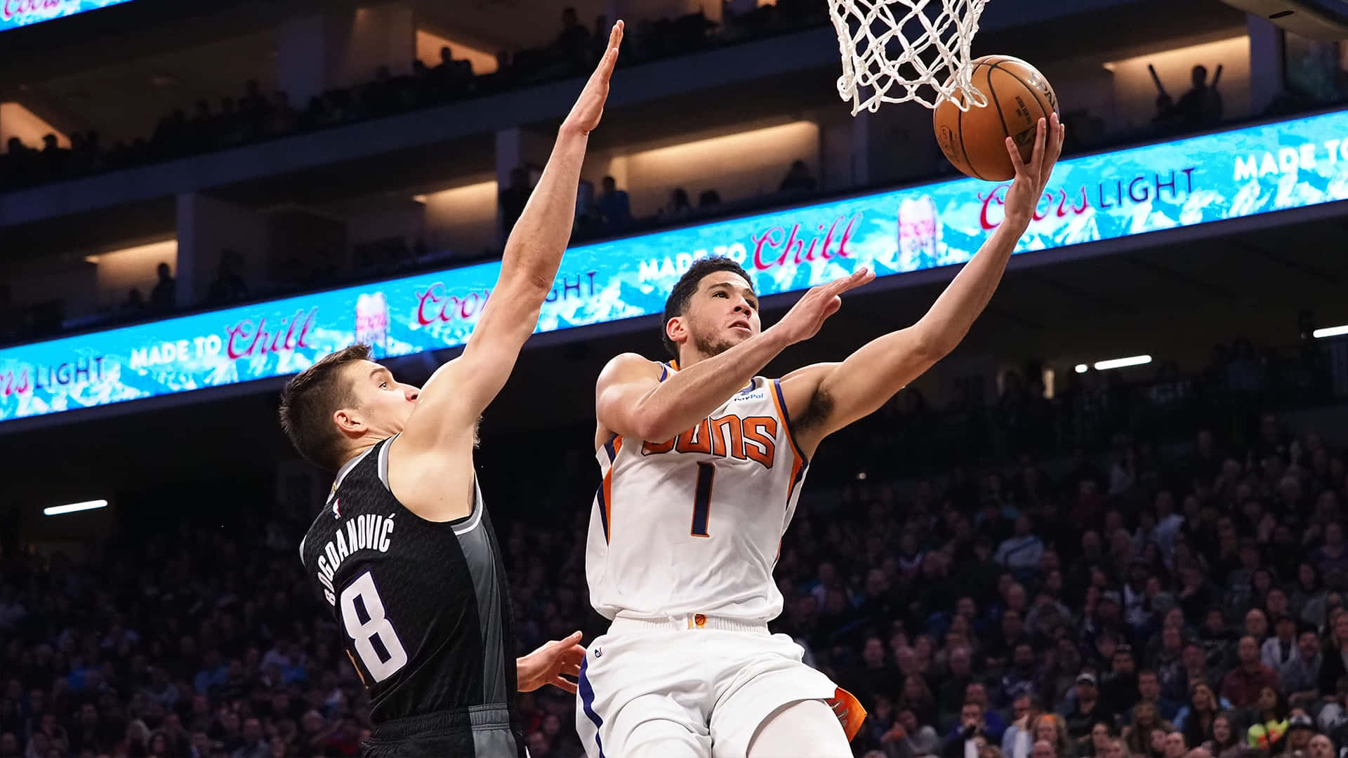 籃球運動員在擠滿觀眾的場館內越過防守球員灌籃。 — NBA 壁紙