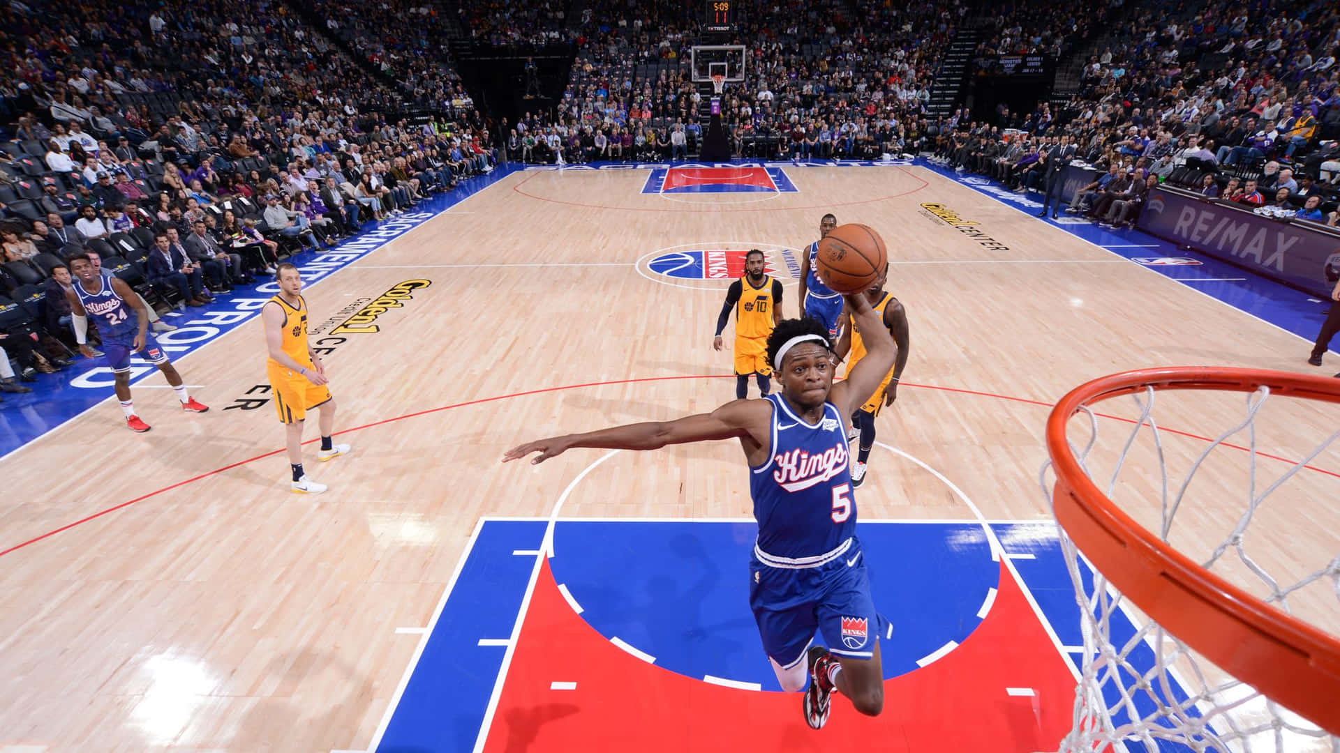 身穿藍色球衣的籃球運動員在比賽中灌籃，觀眾觀看。 — NBA 壁紙