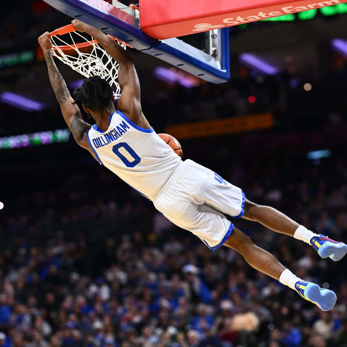 身穿杜克球衣的籃球運動員在觀眾注視的場館中灌籃。 — NBA 壁紙