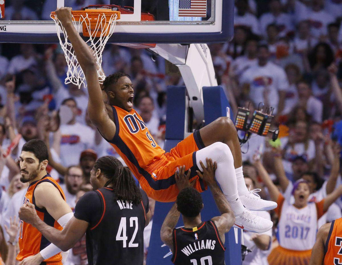籃球運動員得分後吊在籃框上，觀眾歡呼。 — NBA 壁紙