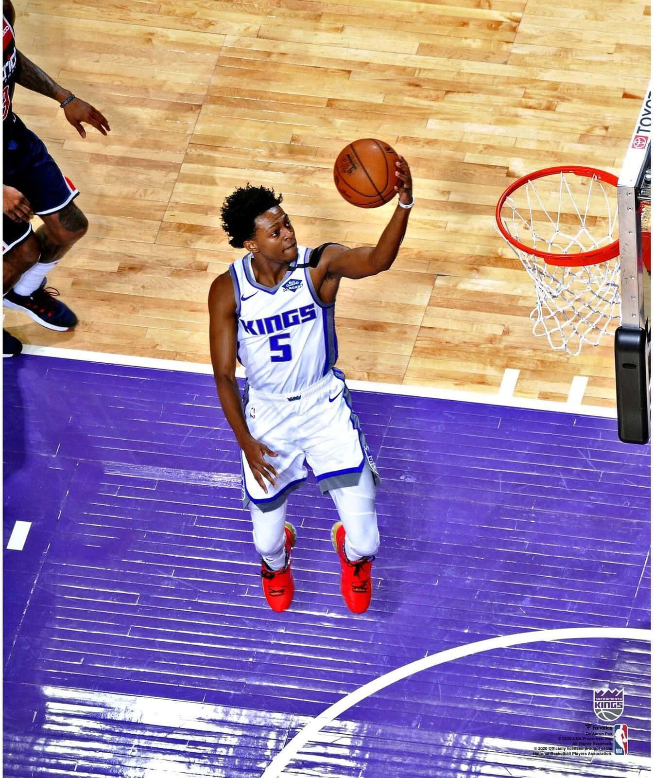 身穿白色球衣的籃球運動員跳起在籃框附近投籃。 — NBA 壁紙