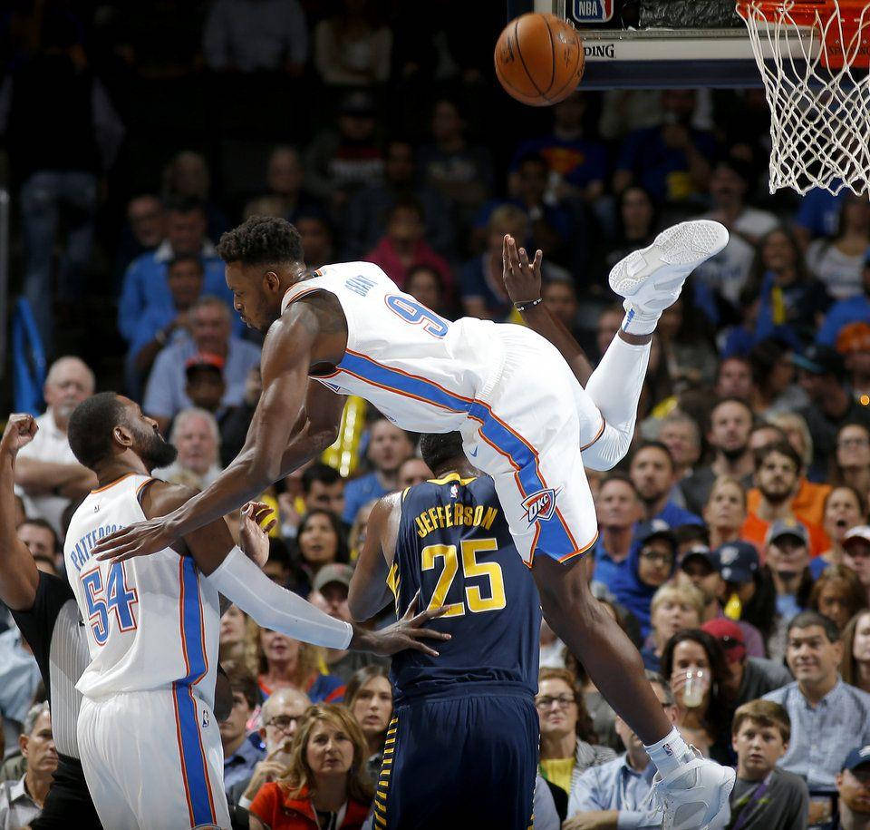 籃球運動員在半空中越過防守球員灌籃，場館內有觀眾。 — NBA 壁紙