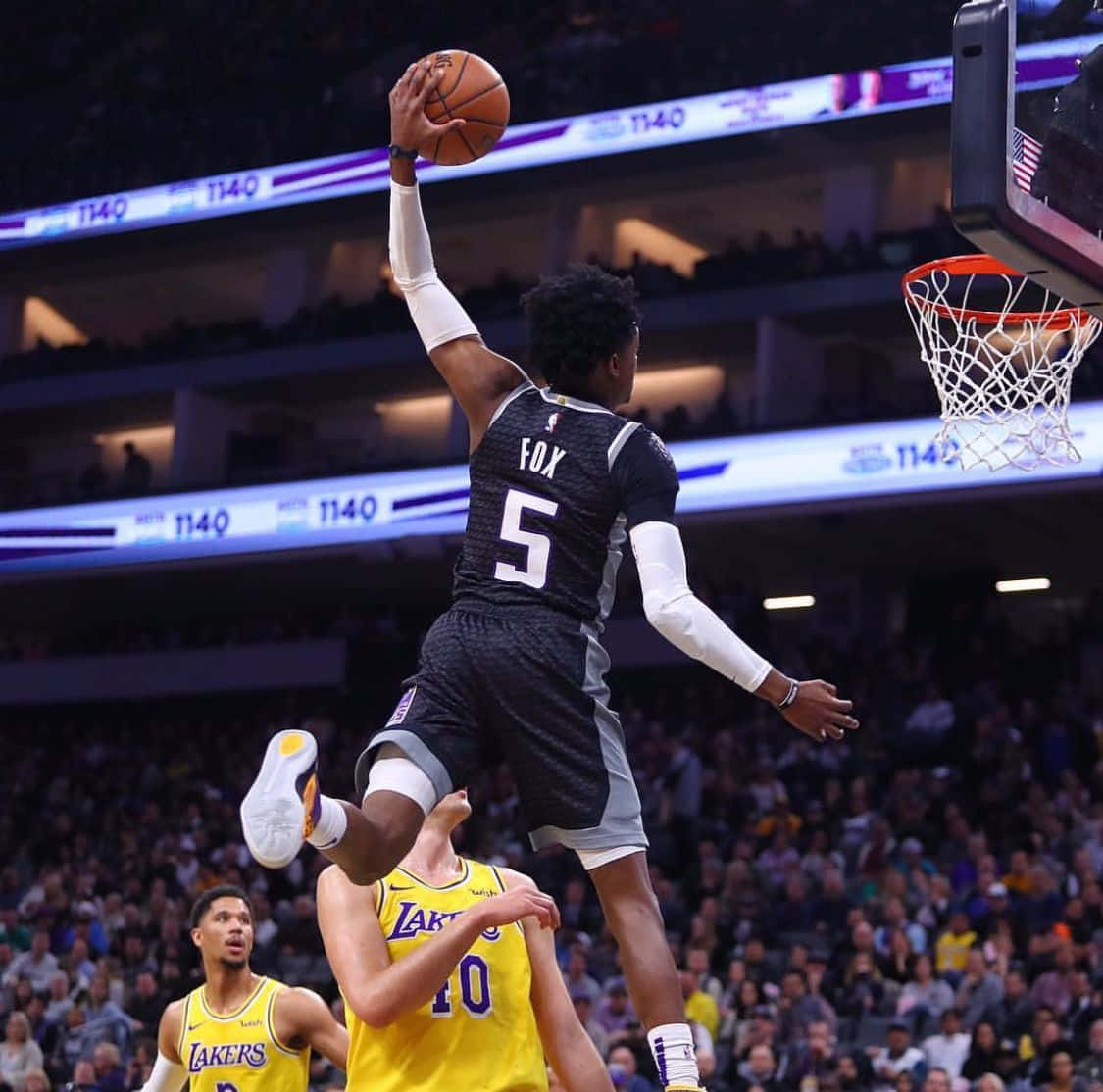 背號5的籃球運動員在擠滿觀眾的場館中越過防守球員灌籃。 — NBA 壁紙
