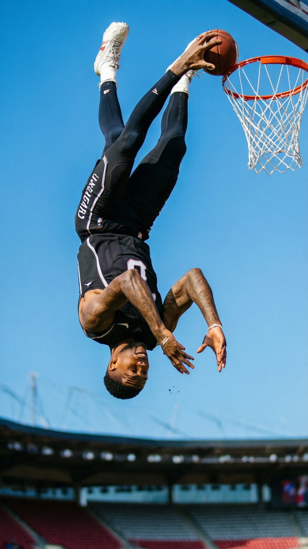 Defying Gravity 壁紙 — 一名籃球運動員倒掛在半空中，將球灌入籃框，背景是清澈的藍天。