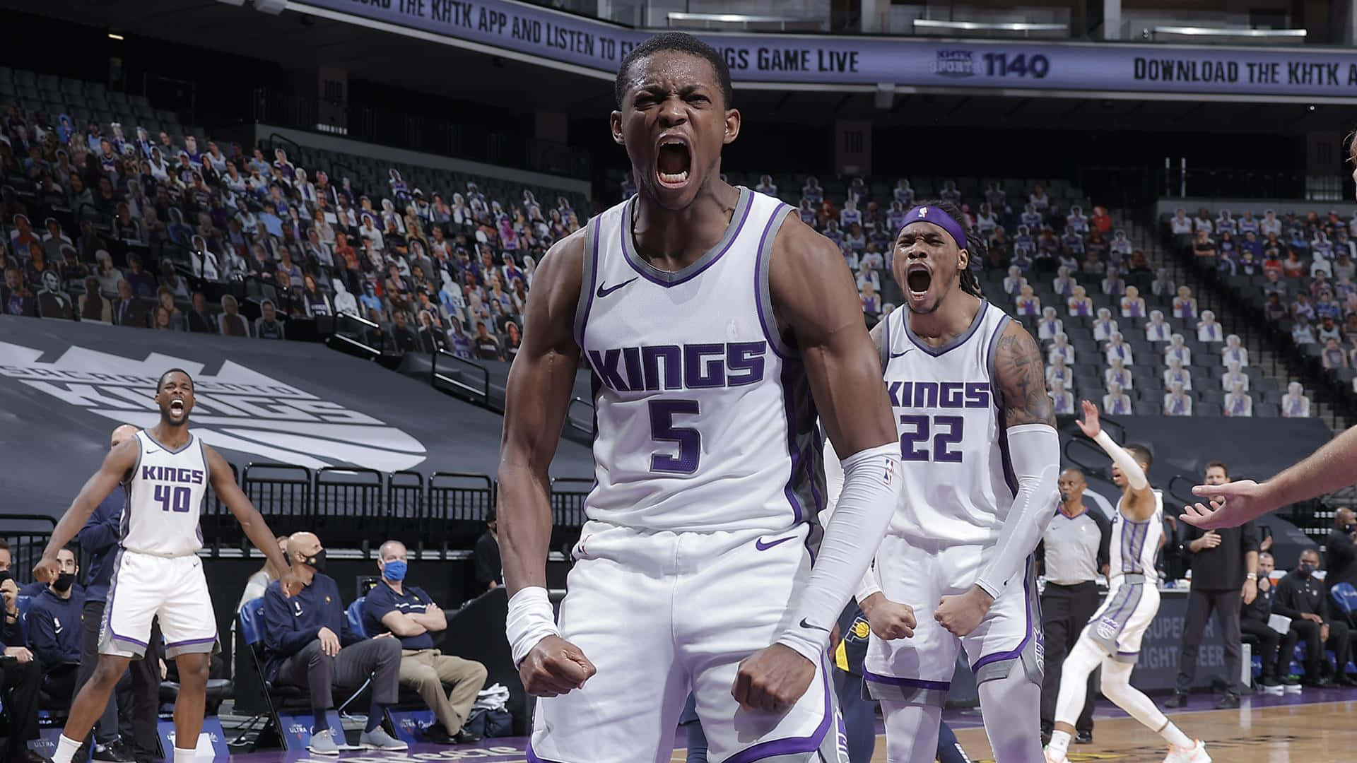身穿Kings球衣的籃球運動員在擠滿觀眾的球場上慶祝勝利。 — NBA 壁紙
