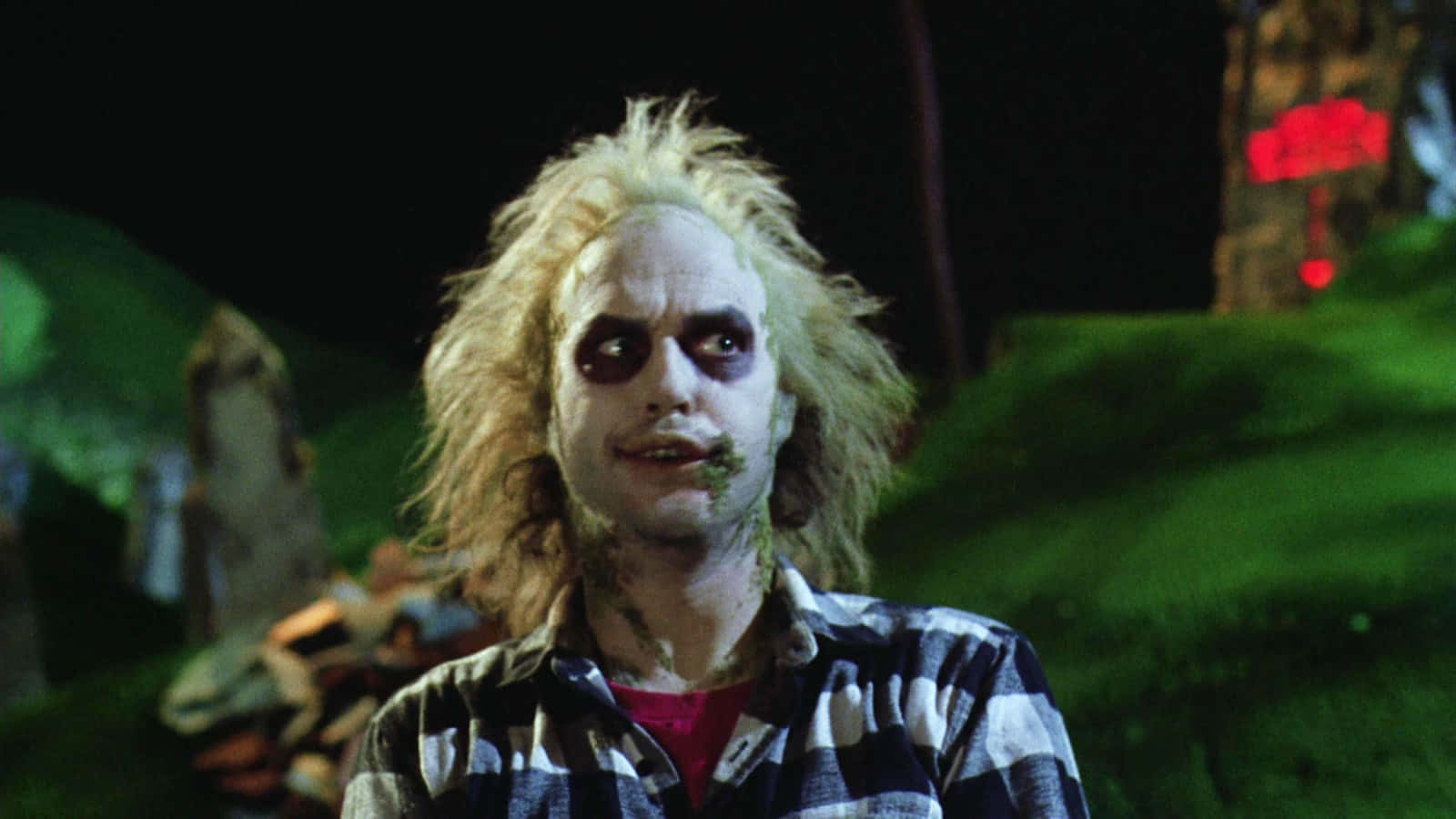  壁紙 — Beetlejuice 擁有狂野的金色頭髮和蒼白的妝容，在深綠色夜空背景下強烈凝視。