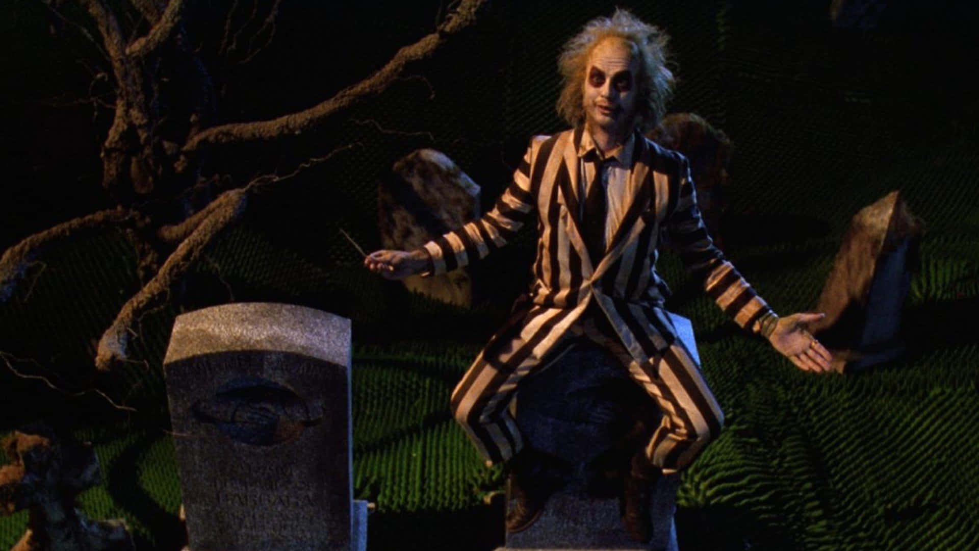  壁紙 — Beetlejuice 坐在黑暗墓園的墓碑上，周圍有扭曲的樹木和陰森的綠色草地，在夜間燈光下。