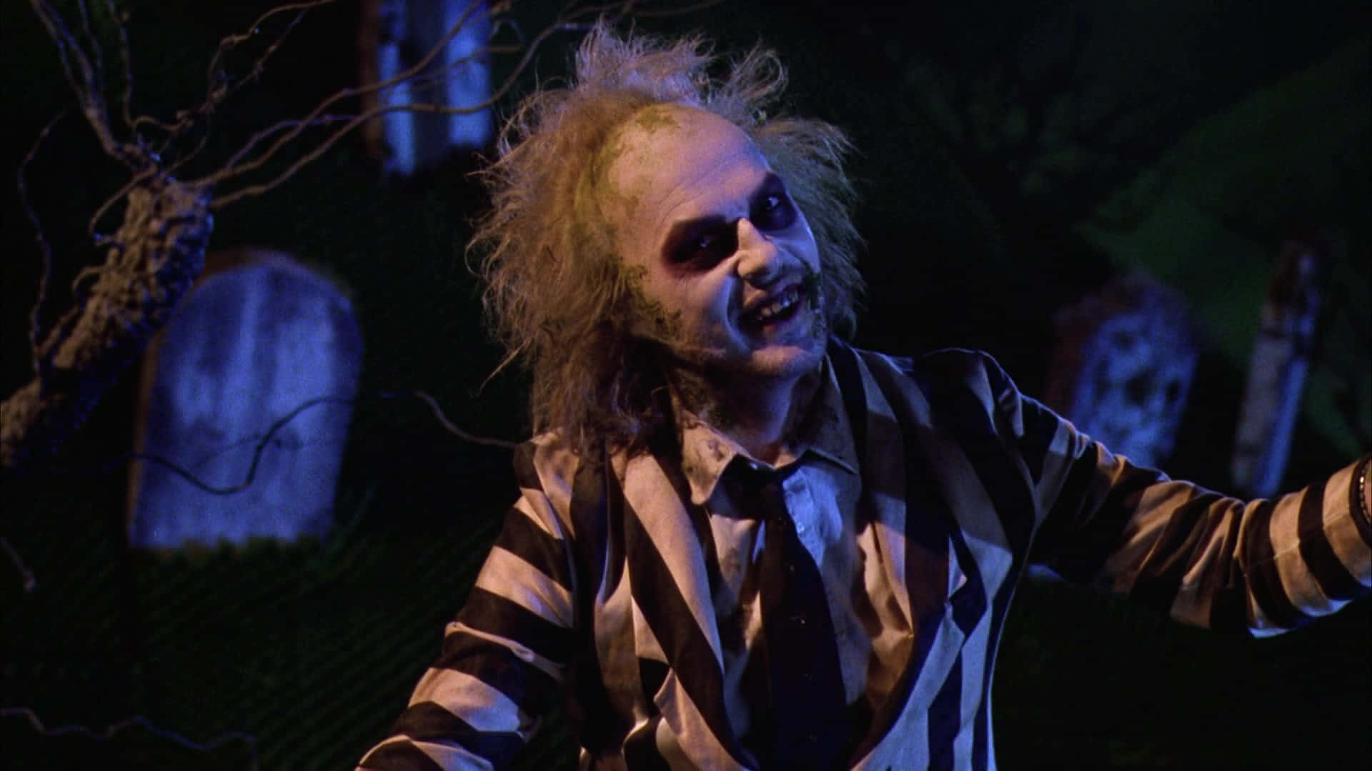 Beetlejuice 桌布 壁紙 — Beetlejuice 穿著其標誌性條紋西裝，在陰森藍光下的黑暗墓地中狂笑。