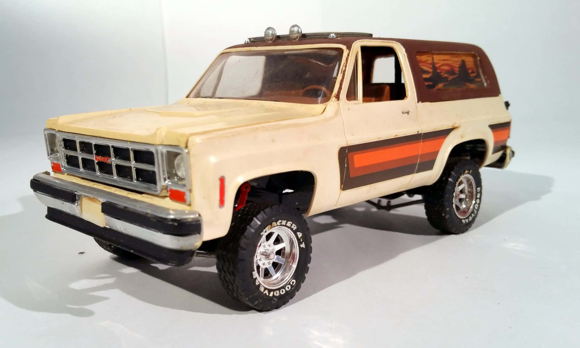 Gmc Jimmy 桌布 壁紙 — 一輛米色和橙色的升高GMC Jimmy模型卡車，配備鍍鉻輪圈和詳細內裝，背景為純白色。