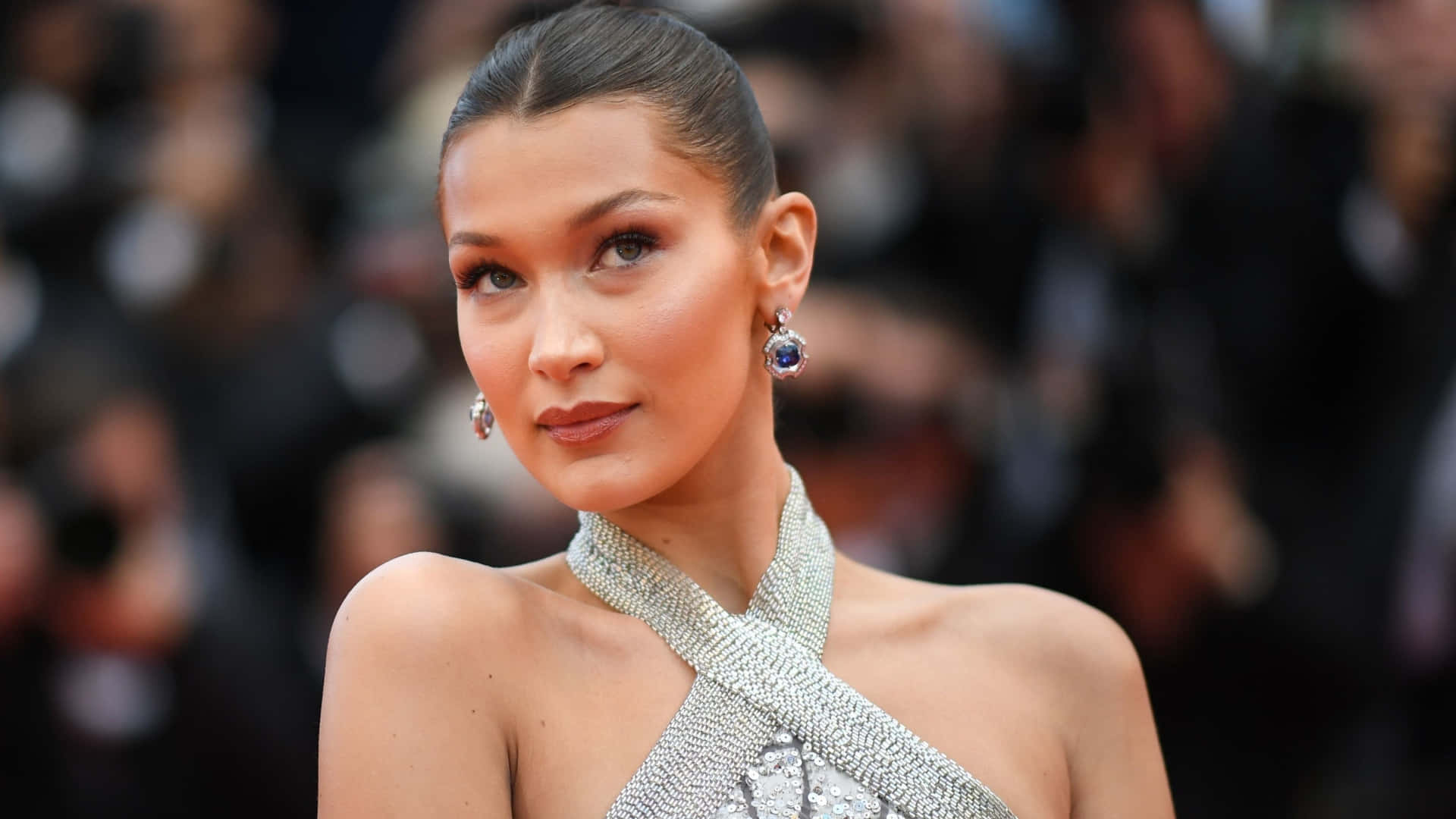 Woman 桌布 壁紙 — Bella Hadid 身穿閃亮銀色長裙，在身後模糊的攝影師襯托下，於華麗的紅地毯活動中閃耀光芒。