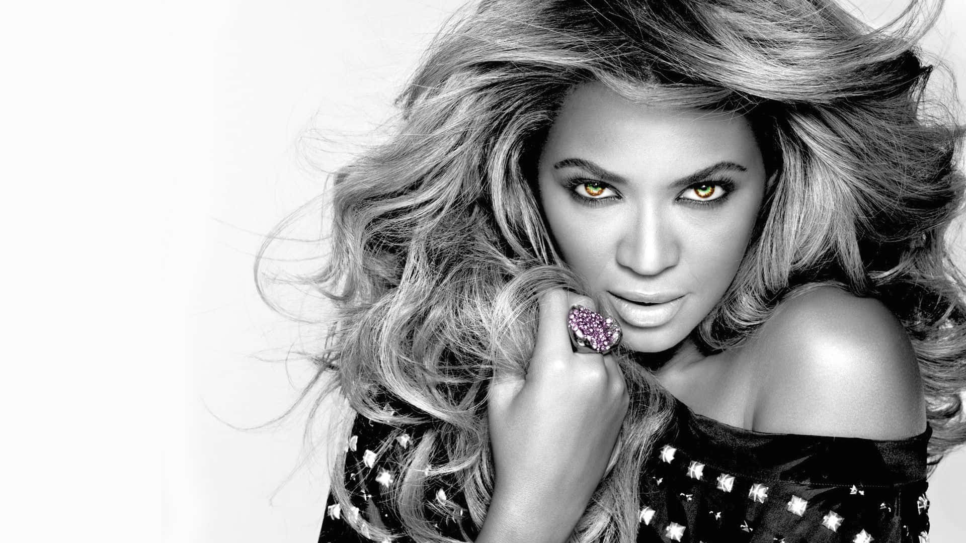 碧昂絲 桌布 壁紙 — Beyoncé 以金色眼睛和飄逸頭髮在高對比黑白肖像中凝視。