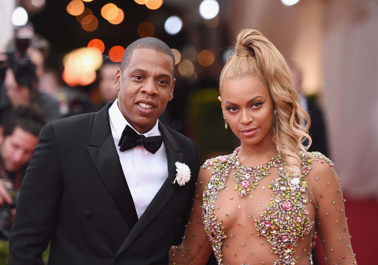 情侶 桌布 壁紙 — Beyoncé 和 Jay-Z 在溫暖的散景燈光下，穿著華麗的正裝，自信地在紅地毯上擺姿勢。
