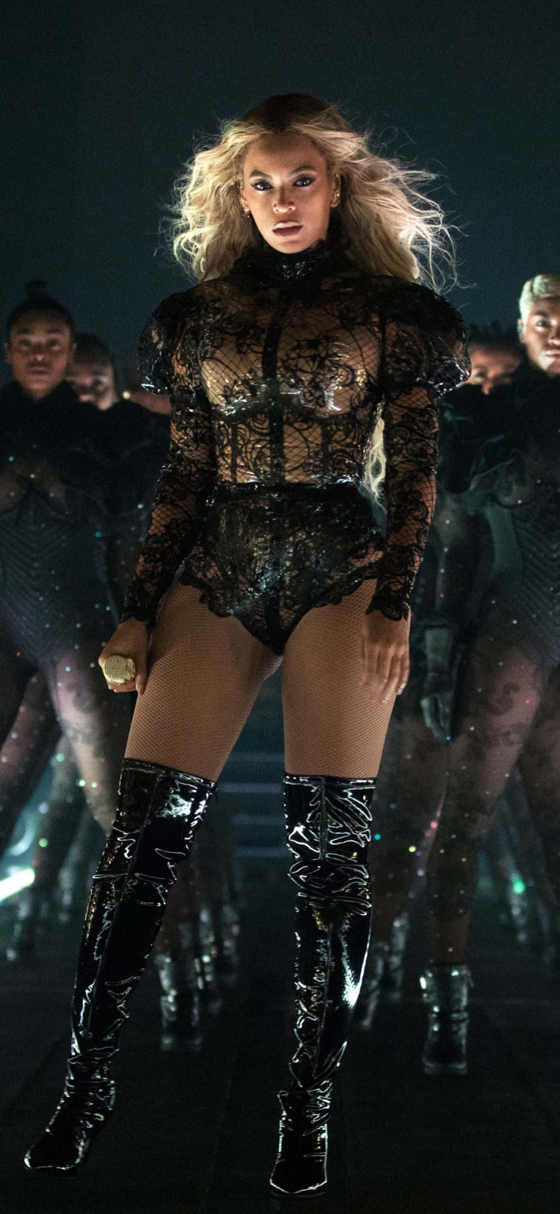 碧昂絲 桌布 壁紙 — Beyoncé 在戲劇性的舞台燈光下，身穿黑色蕾絲連體衣和過膝長靴，主宰舞台。