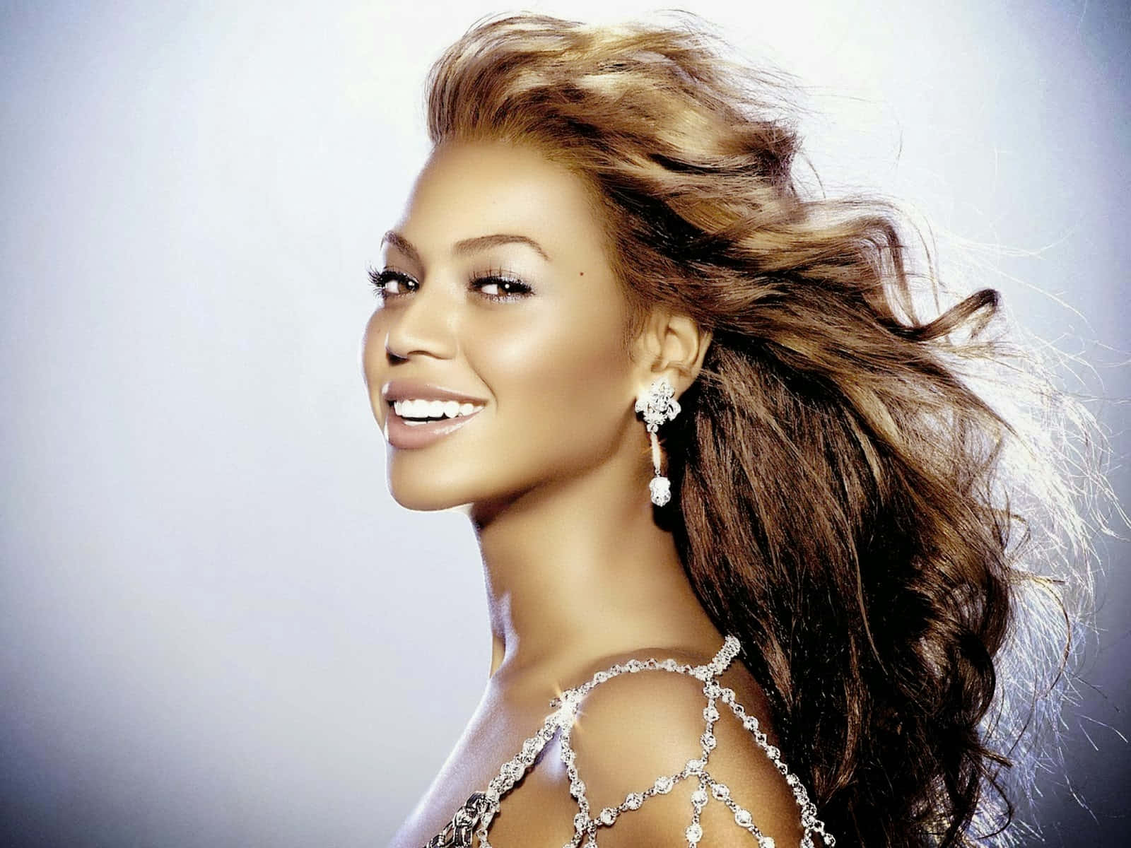 碧昂絲 桌布 壁紙 — Beyoncé 在柔和的漸變背景前，秀髮飄逸，閃爍的鑽石耳環，燦爛微笑。