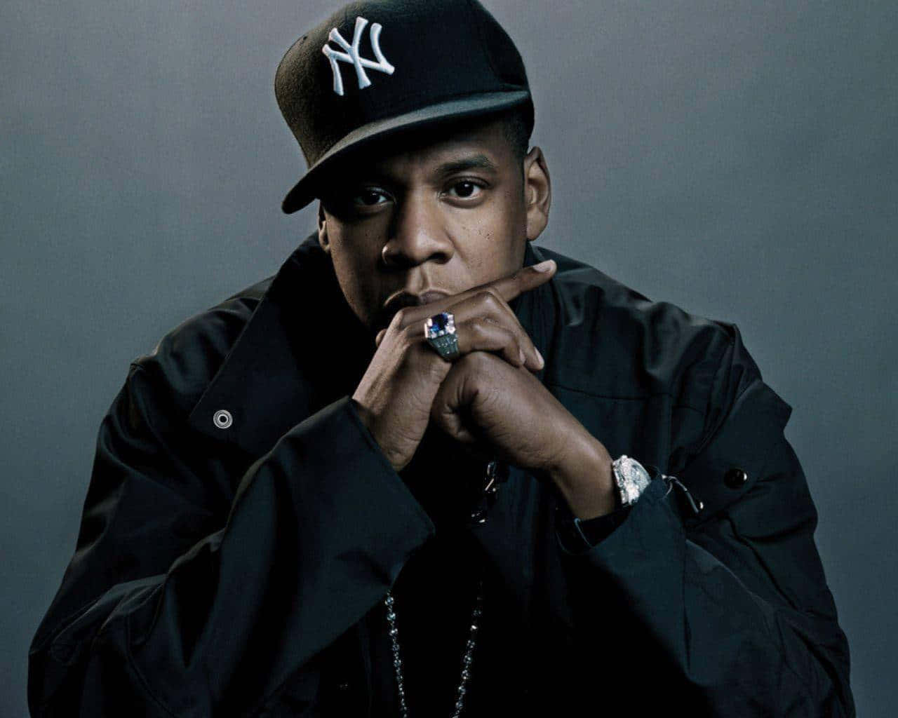 桌布 壁紙 — Beyoncé 雙手交疊在下巴下方，戴著黑色NY帽和外套，在灰色背景前凝視。