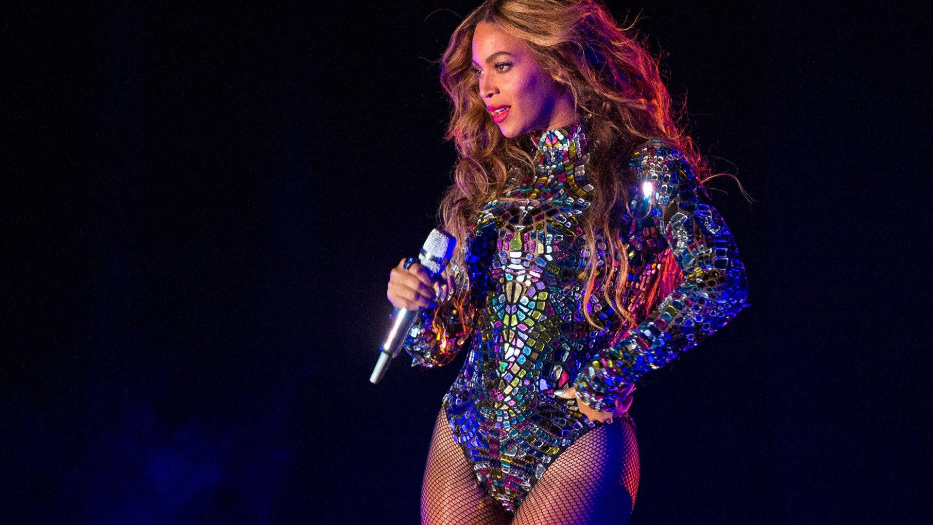 碧昂絲 桌布 壁紙 — Beyonce 在舞台上穿著閃耀的馬賽克緊身衣，在充滿活力的舞台燈光下表演。