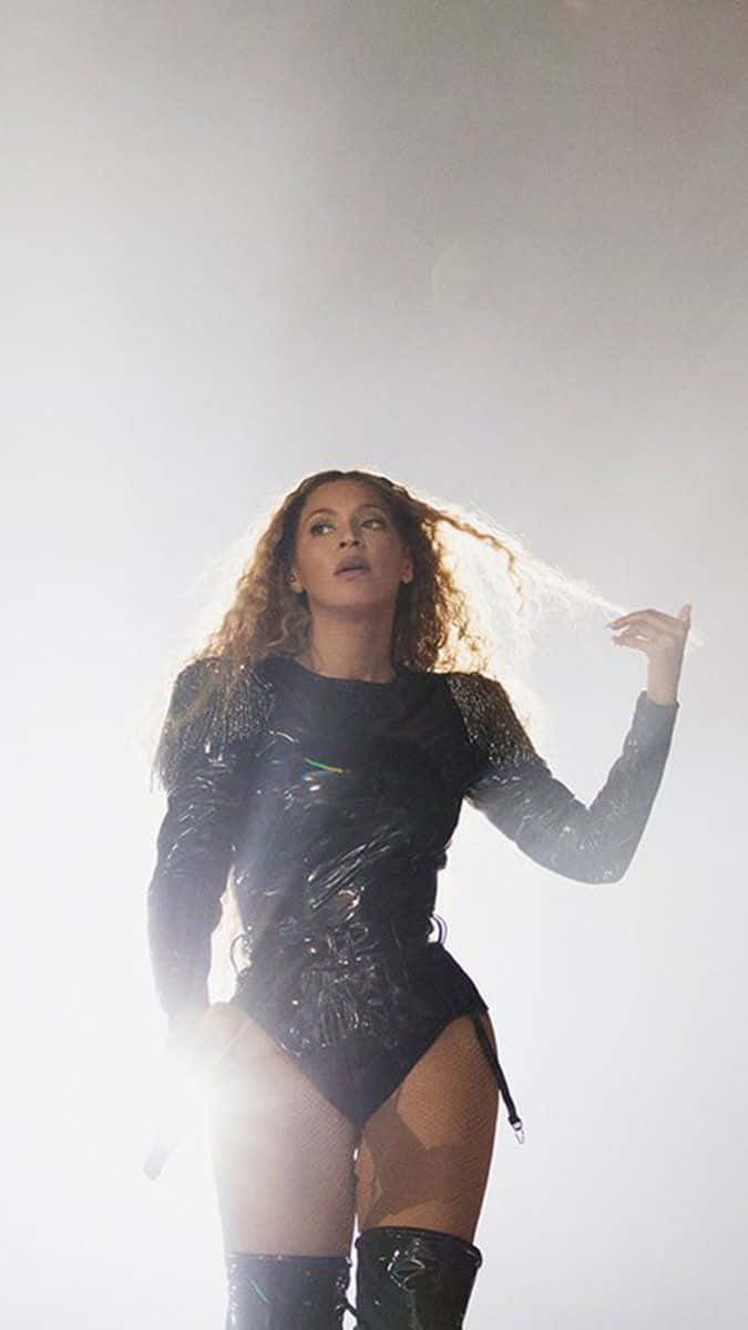 碧昂絲 桌布 壁紙 — Beyonce 身穿閃亮黑色連體衣，在明亮的舞台燈光下表演，秀髮飄逸。