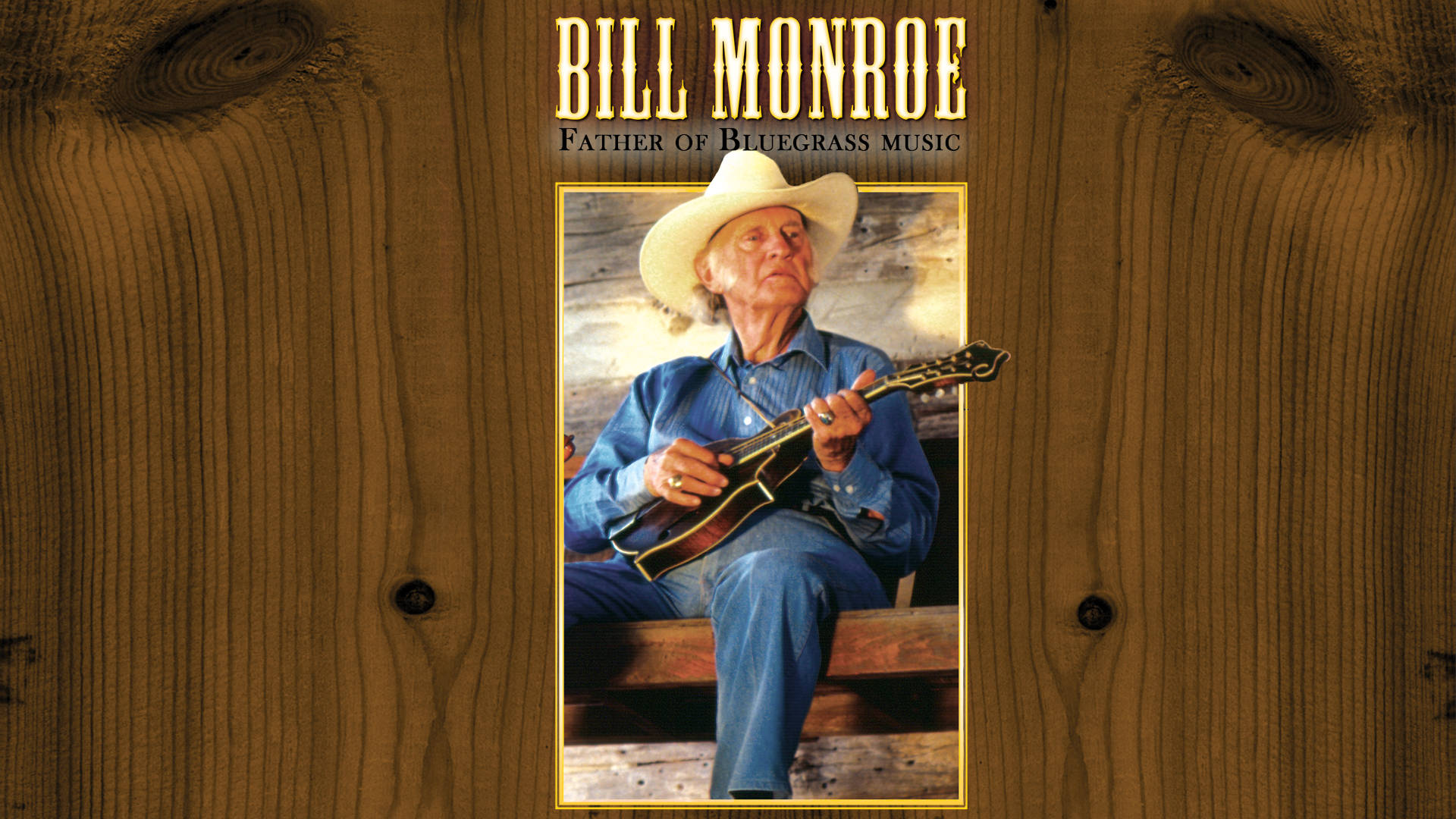 音樂 桌布 壁紙 — Bill Monroe 戴著白色帽子和藍色襯衫，坐在木階梯上彈奏曼陀林，背景是質樸的木鑲板。