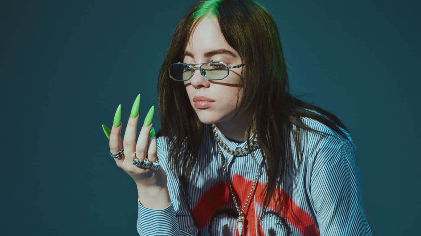 Billie Eilish Laptop 桌布 壁紙 — Billie Eilish 以螢光綠色指甲和眼鏡在深色青綠背景前擺姿勢。