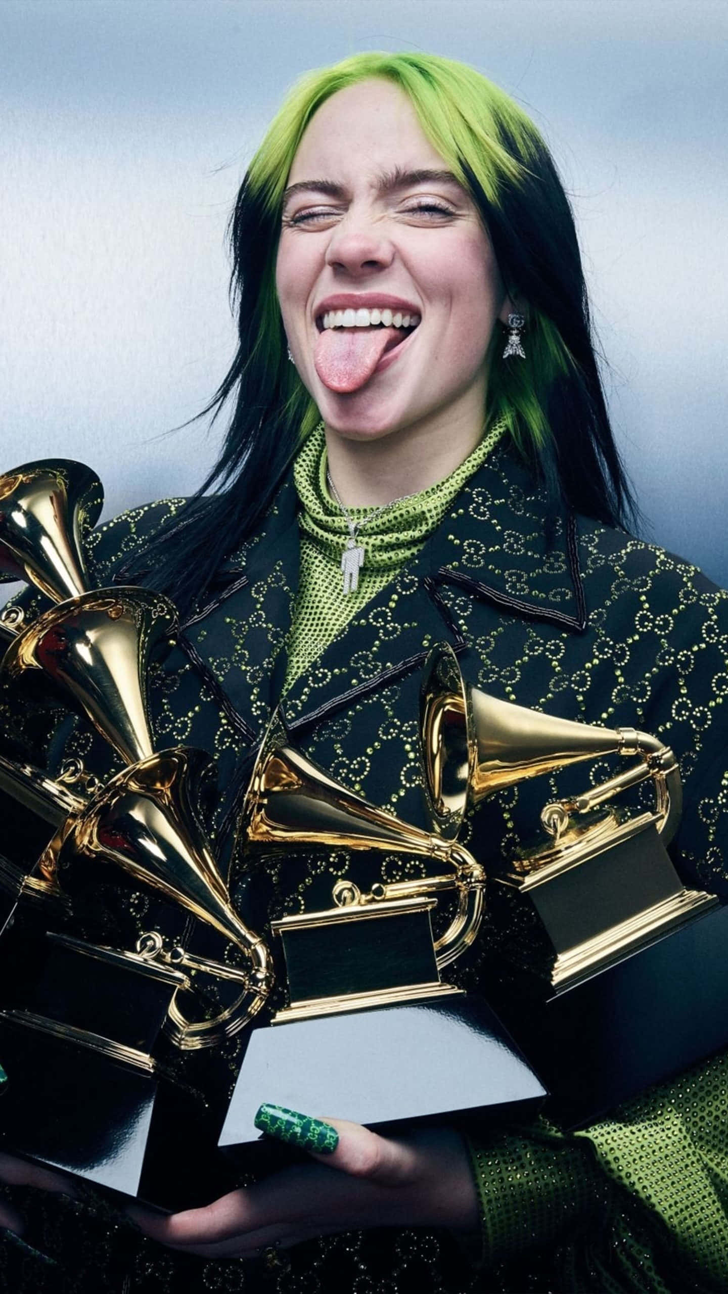 怪奇比莉 桌布 壁紙 — Billie Eilish 伸出舌頭，搞笑地笑著，同時手持多個金色葛萊美獎項。