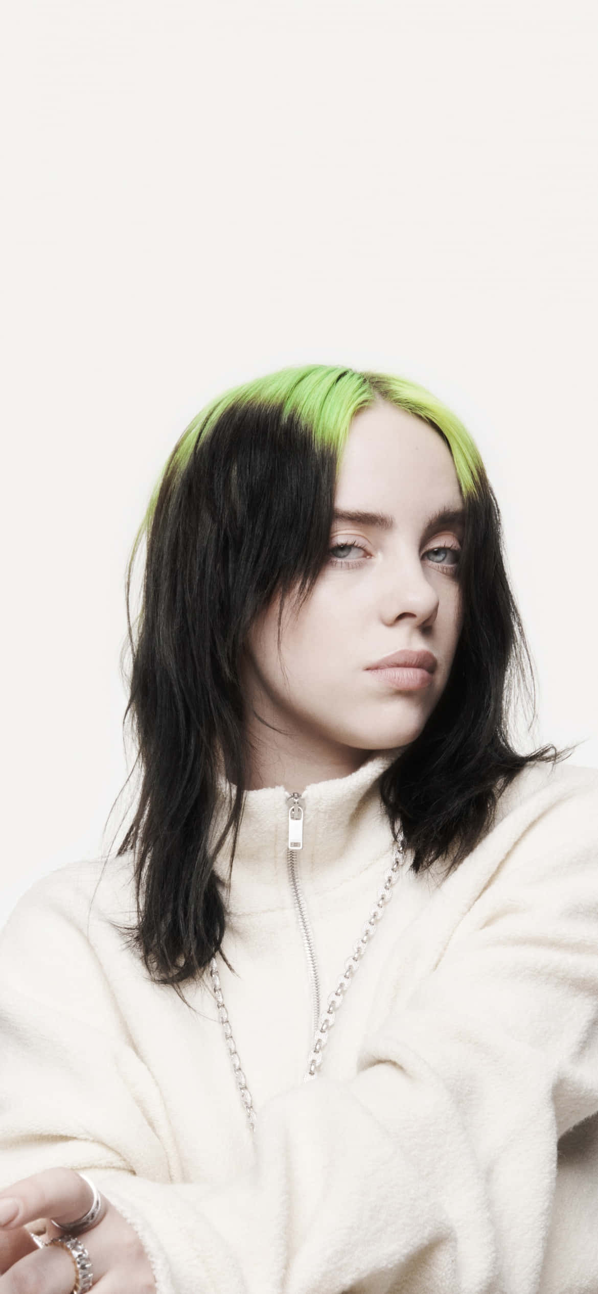 怪奇比莉 桌布 壁紙 — Billie Eilish 帶有螢光綠色髮絲，在純白背景下溫柔凝視，穿著舒適的奶油色拉鍊連帽衫。