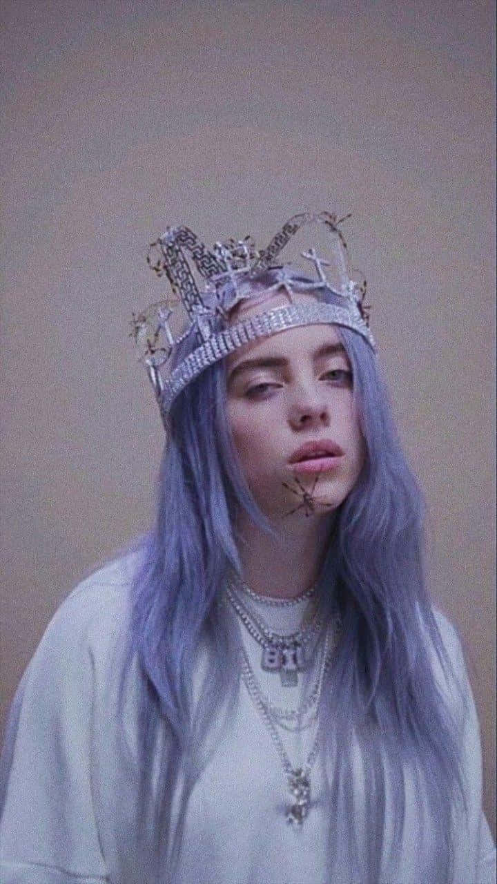 photography iPhone 桌布 壁紙 — Billie Eilish 擁有薰衣草色頭髮和鑲有寶石的王冠，在柔和的米色背景前溫柔地凝視。