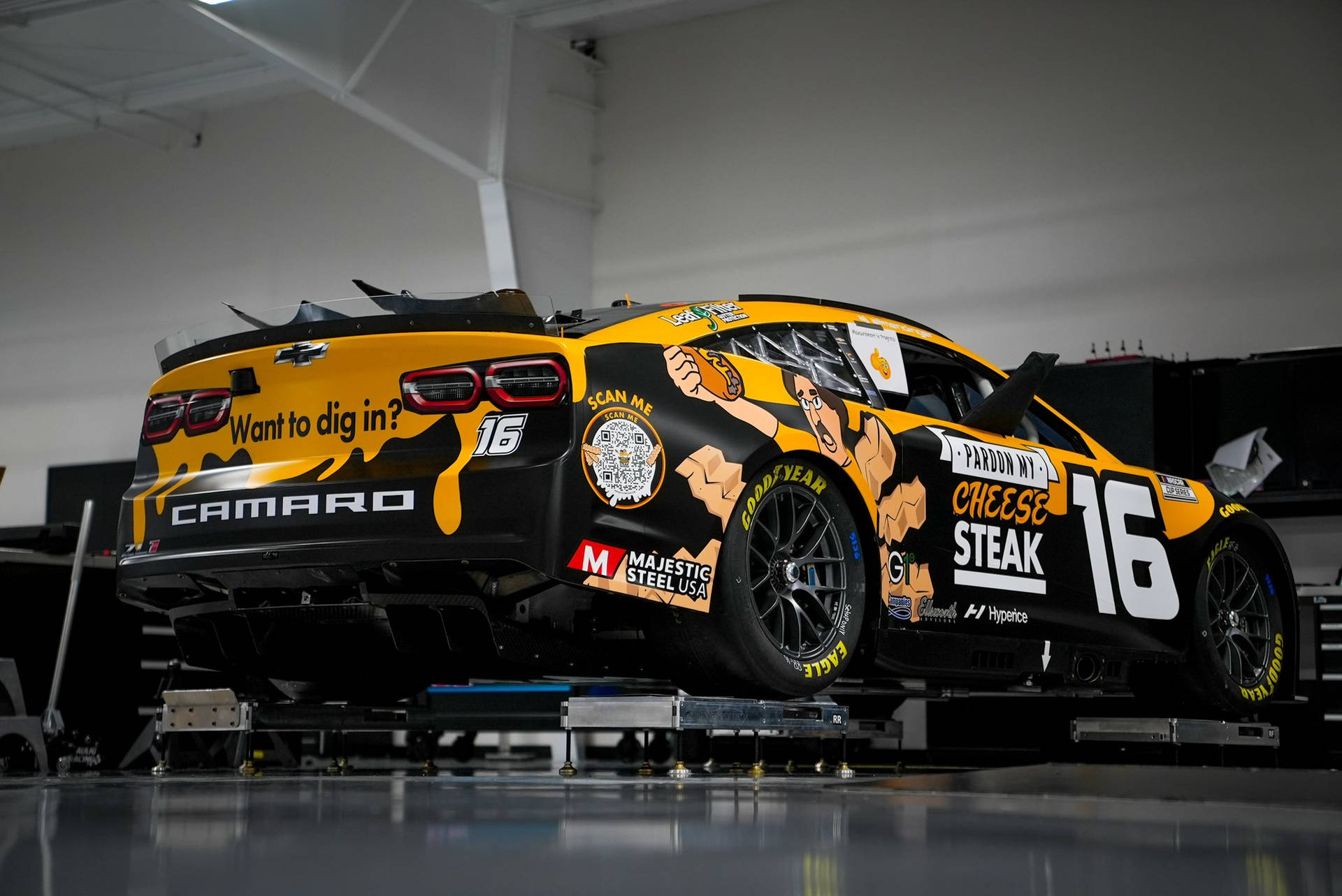車庫內帶有起司牛排廣告的黑黃色NASCAR賽車。 — 肌肉車 壁紙