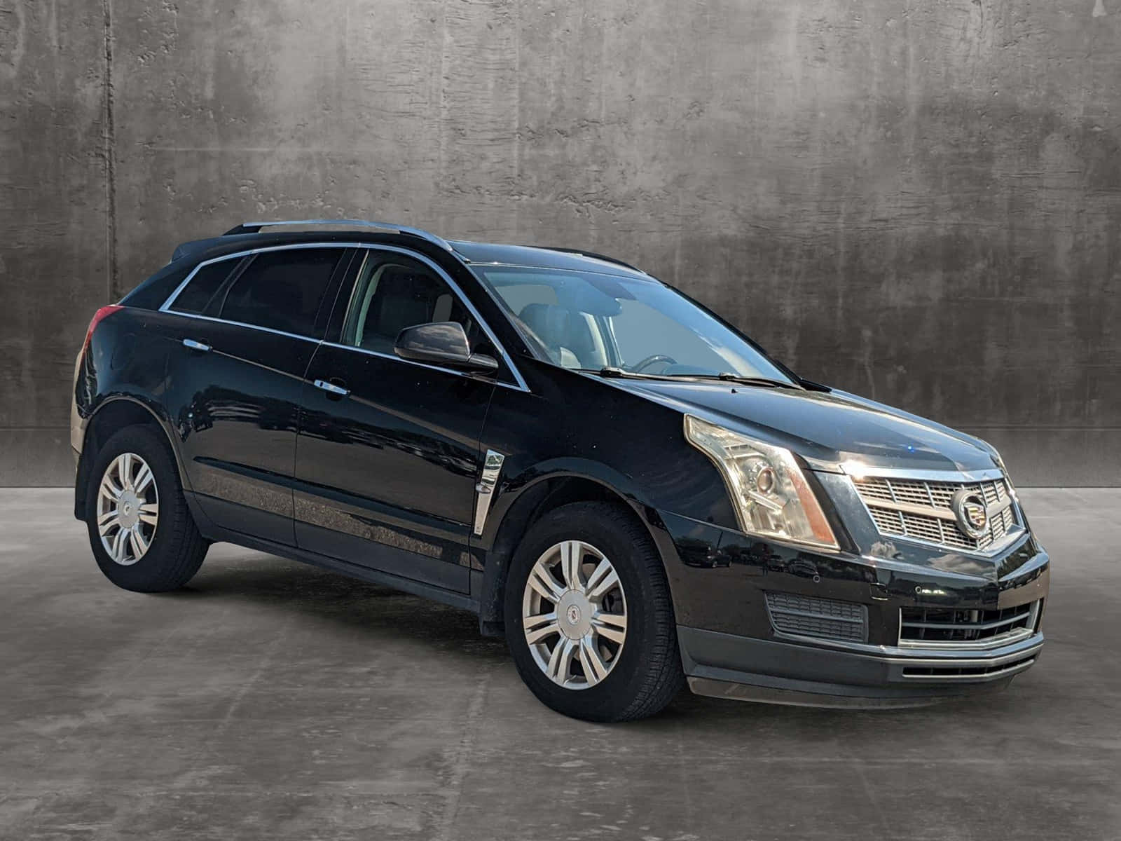 Cadillac Srx 桌布 壁紙 — 一輛時尚的黑色 Cadillac SRX SUV 在攝影棚燈光下，以紋理灰色混凝土牆為背景閃閃發光。