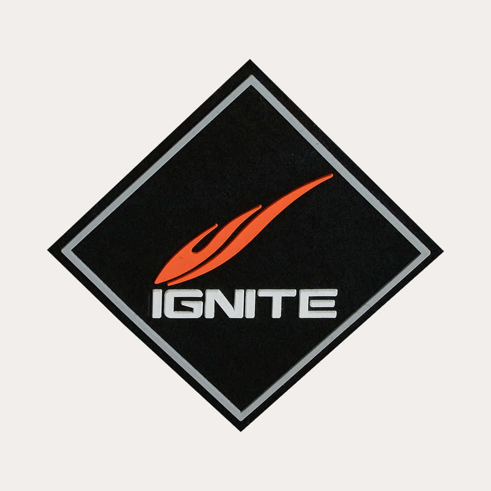  壁紙 — 一個黑色菱形貼片，上面有橙色火焰標誌和白色「IGNITE」文字，背景為淺灰色。
