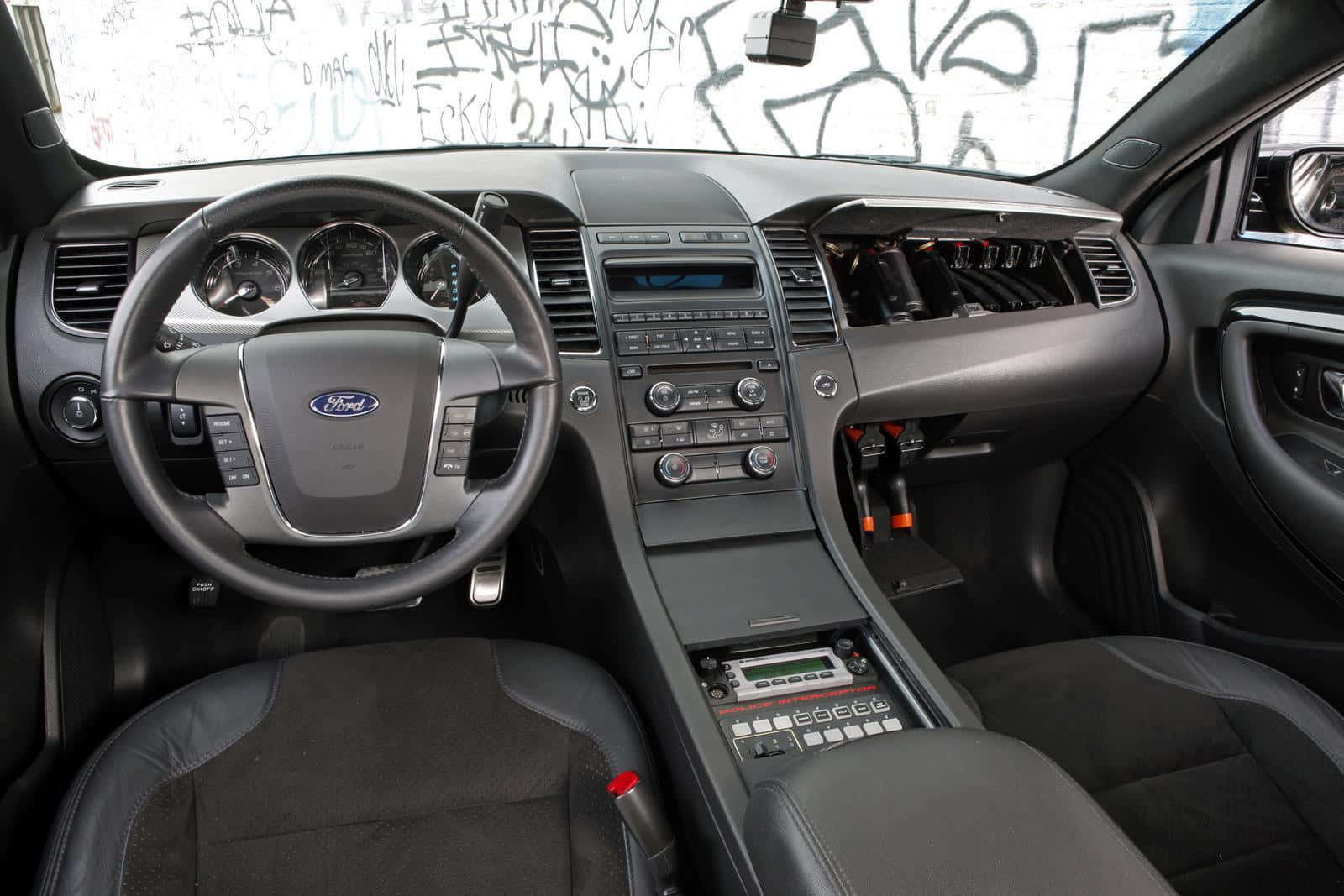 Ford Taurus 桌布 壁紙 — 黑色福特汽車內部，詳細的儀表板和方向盤，從駕駛座視角，車窗被塗鴉覆蓋。