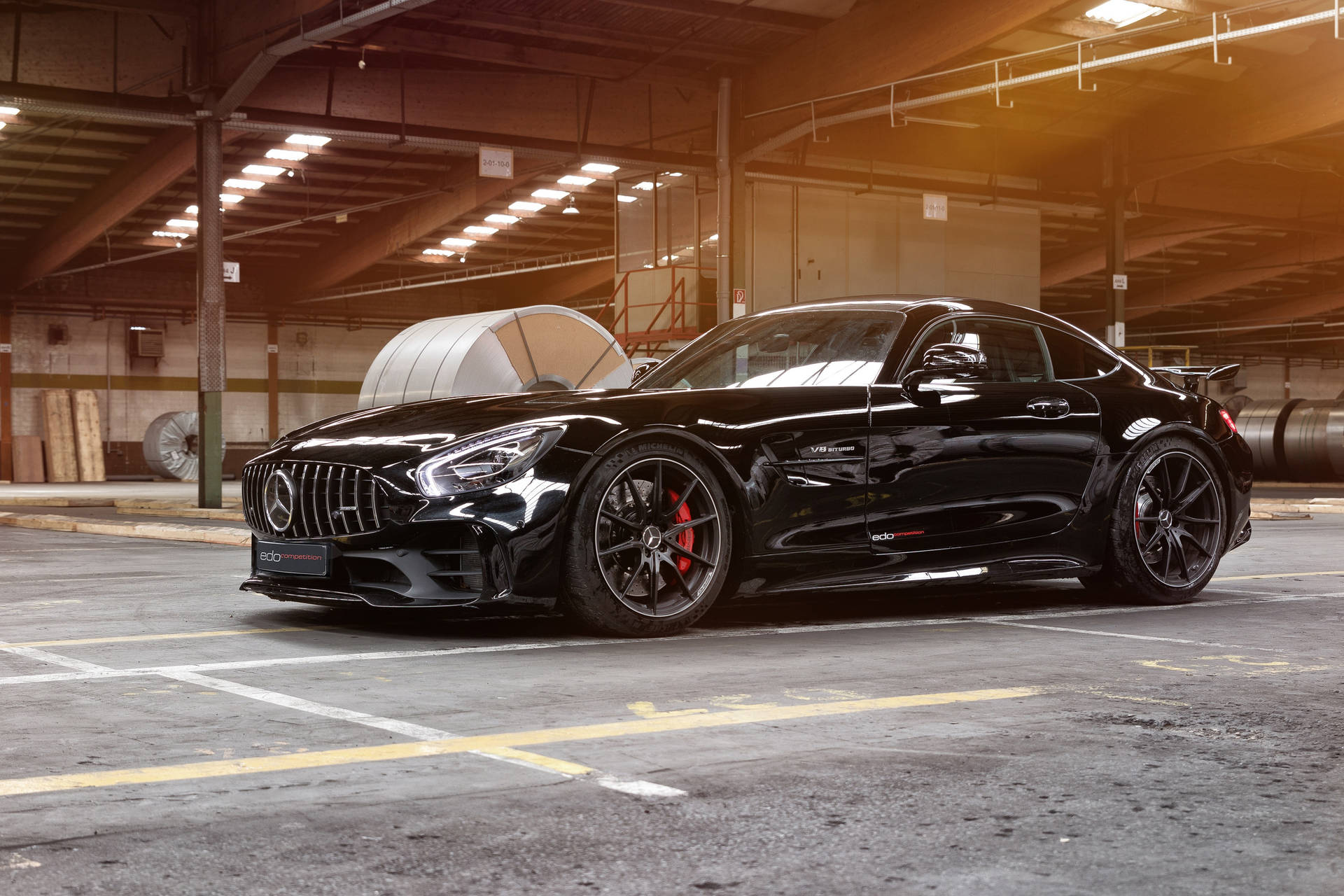 黑色 Mercedes-AMG GT R 停放在工業倉庫中，紅色制動卡鉗清晰可見。 — Amg Gt R 壁紙