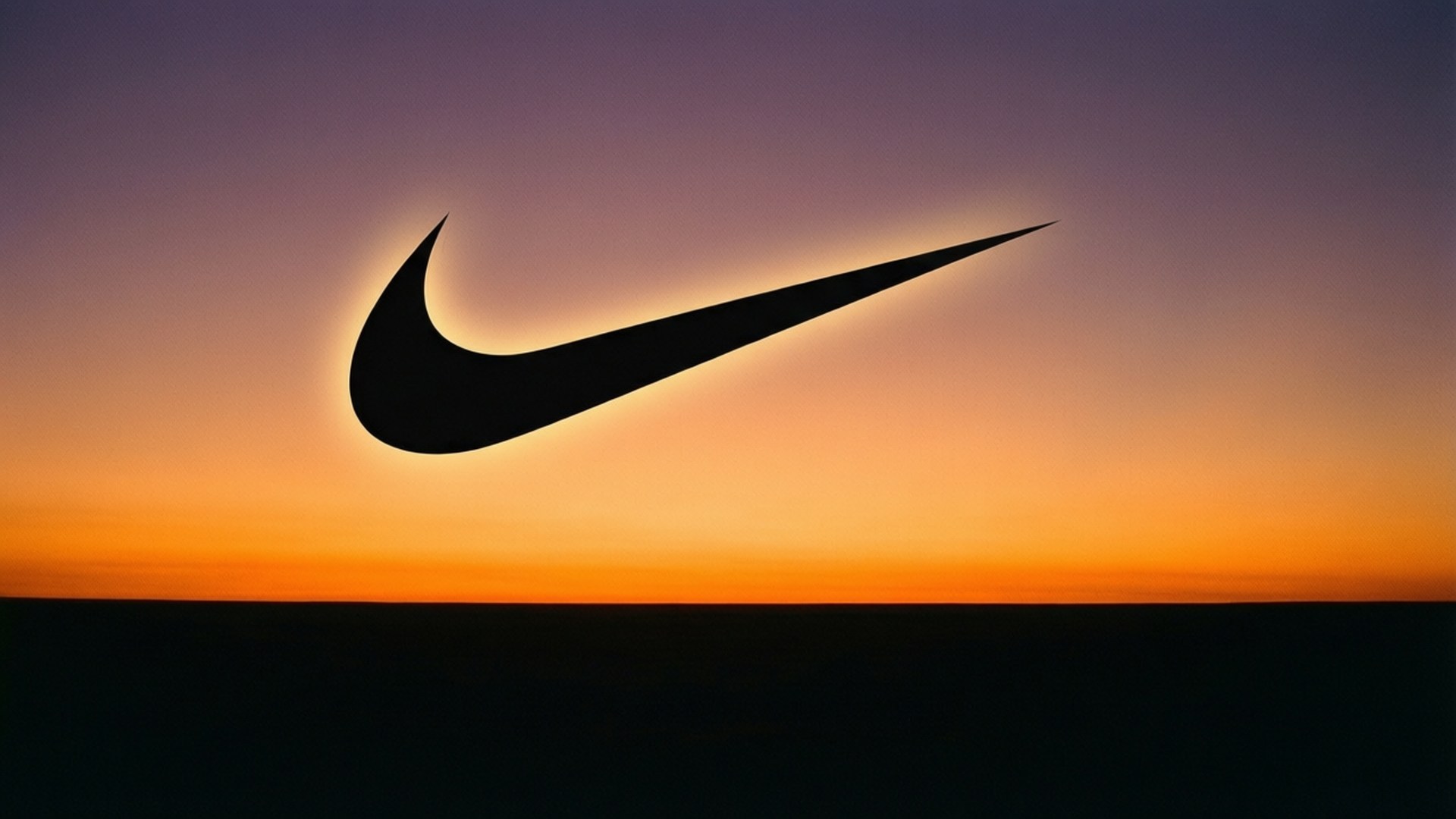 Swoosh Sunset 壁紙 — 黑色Nike勾形標誌剪影，襯托著由橙色漸變至紫色的鮮豔日落天空。