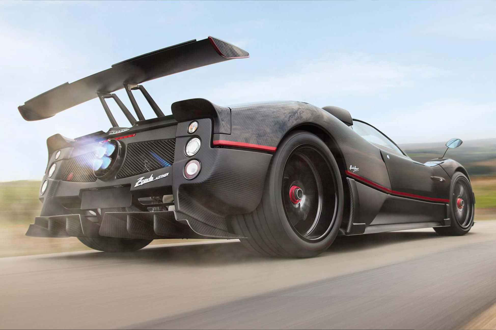 Pagani Zonda C12 Roadster 桌布 壁紙 — 一輛黑色Pagani Zonda跑車帶有紅色點綴，在道路上疾馳，背景是模糊的風景。