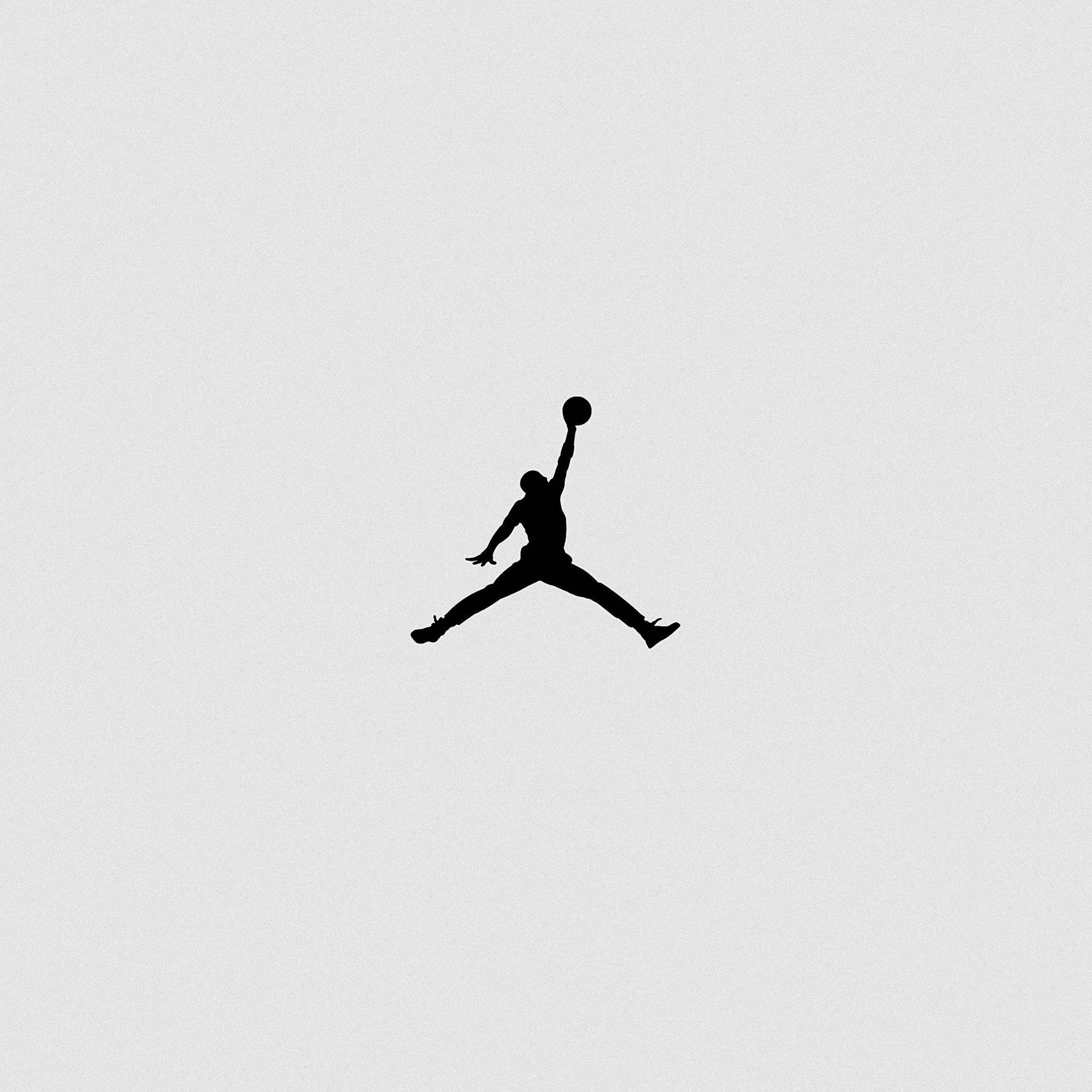 黑色剪影，一名籃球運動員跳起在淺灰色背景上灌籃。 — Jordan Logo 壁紙