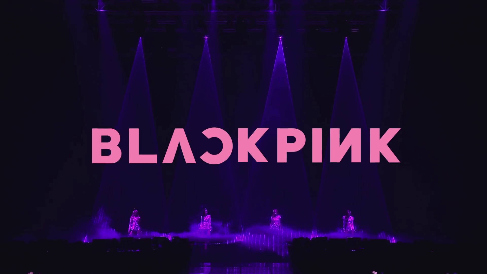 BLACKPINK 桌布 壁紙 — Blackpink 在戲劇性的紫色聚光燈下表演，她們的名字在黑暗的舞台上閃耀著粉紅色。