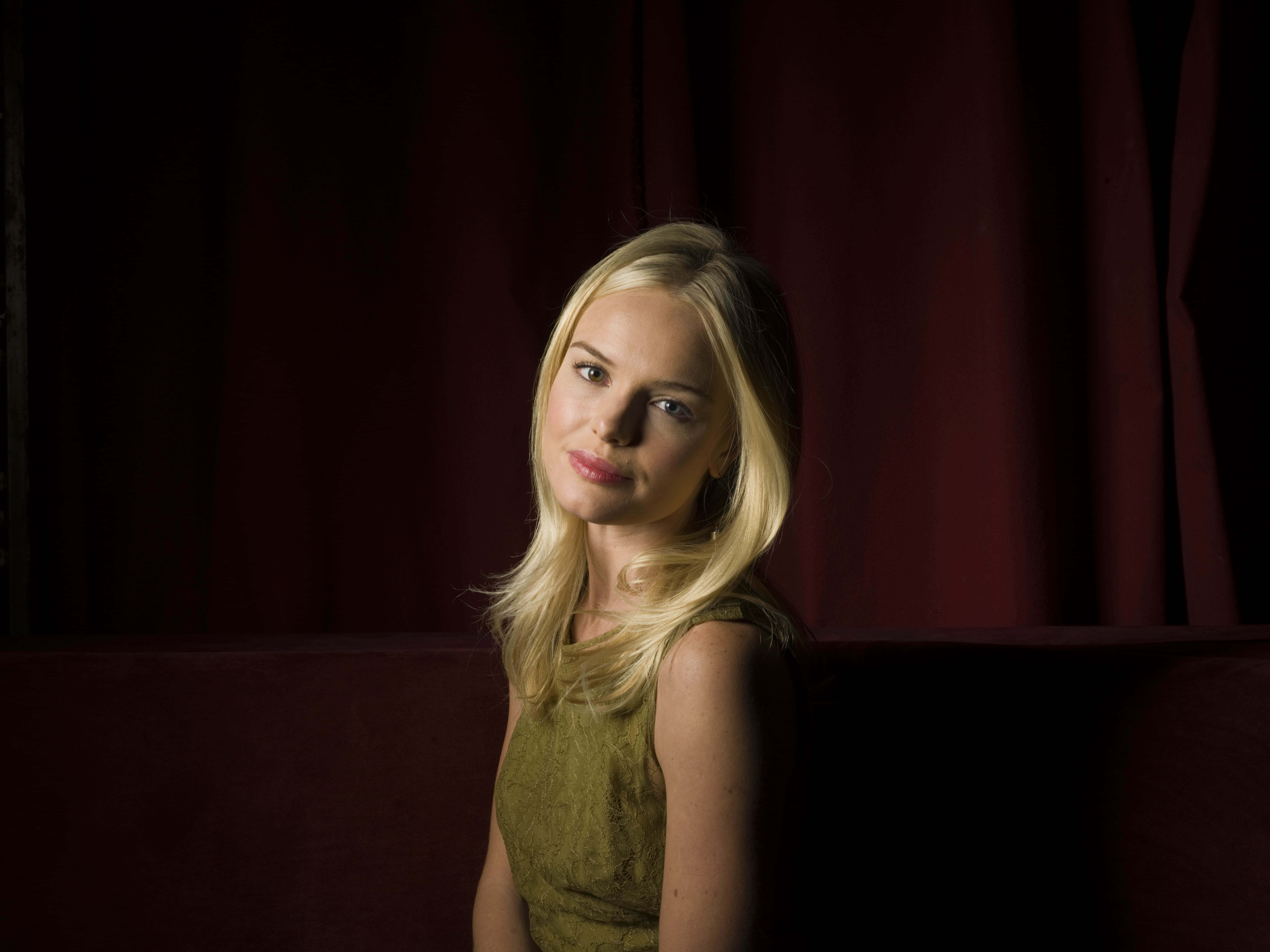 Kate Bosworth 桌布 壁紙 — 一位金髮女子身穿綠色連衣裙，坐在深紅色窗簾前，沐浴在戲劇性的側光中。