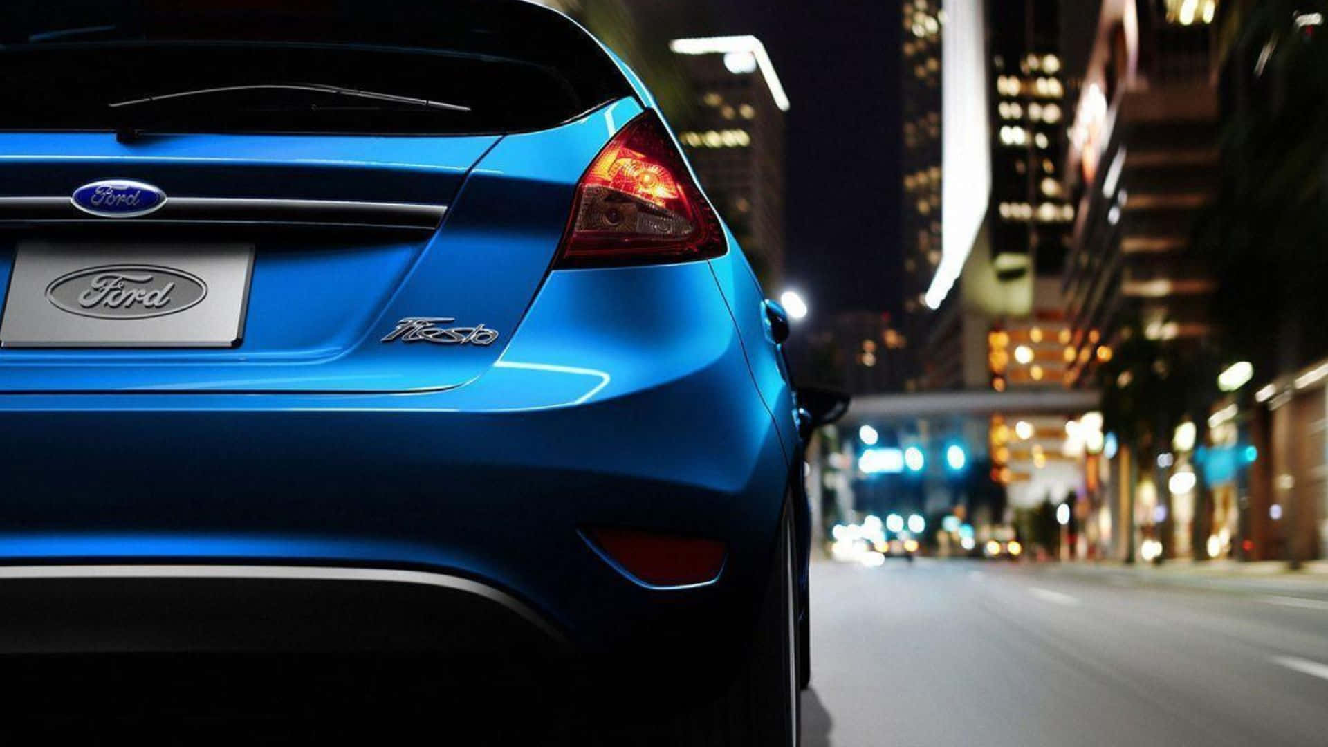 Ford Fiesta 桌布 壁紙 — 一輛充滿活力的藍色福特Fiesta在夜晚行駛於霓虹燈照耀的街道上，背景有模糊的燈光。