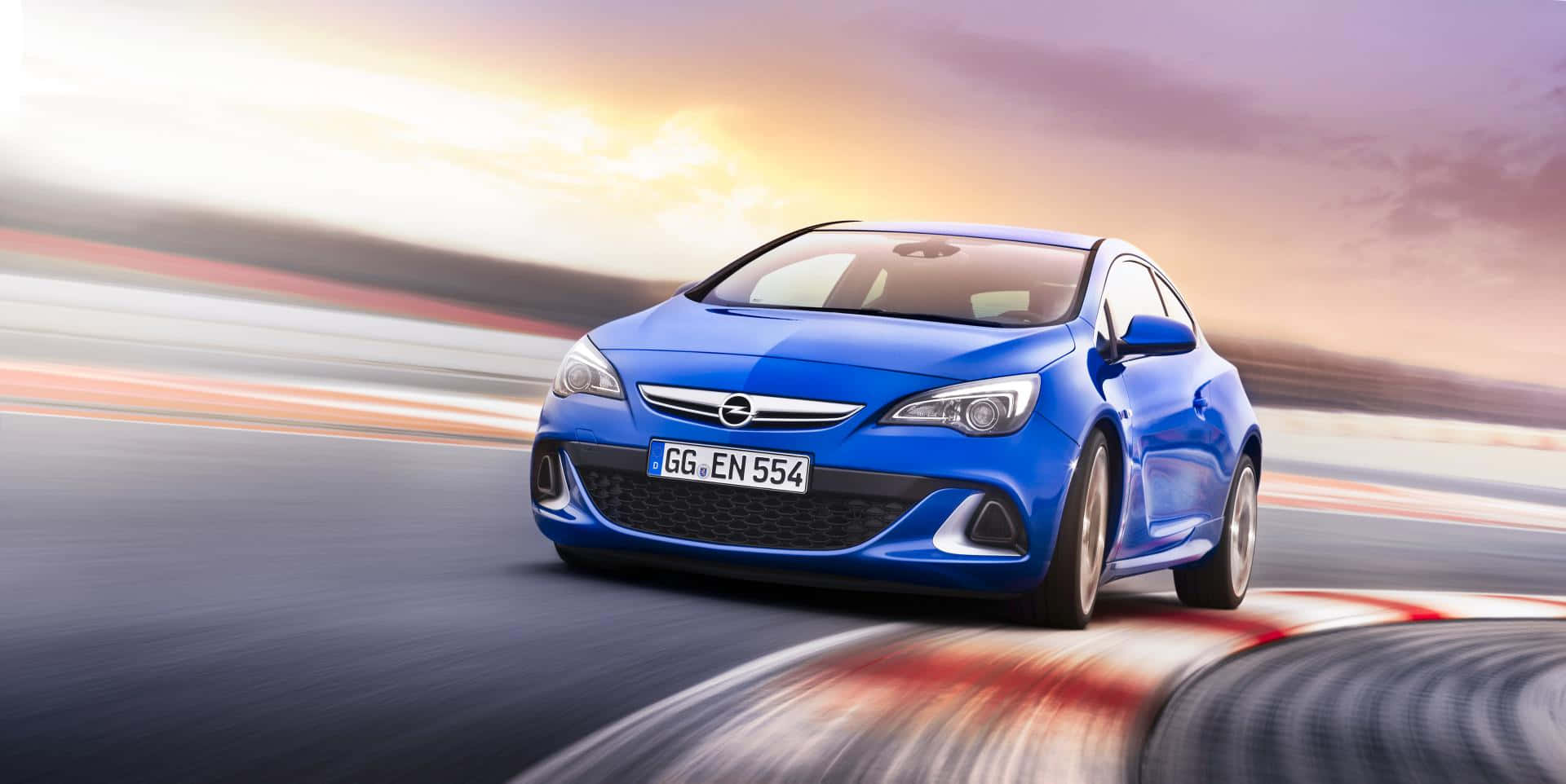Opel Astra 桌布 壁紙 — 一輛充滿活力的藍色跑車在日落時分沿著賽道飛馳，背景帶有動態模糊效果。