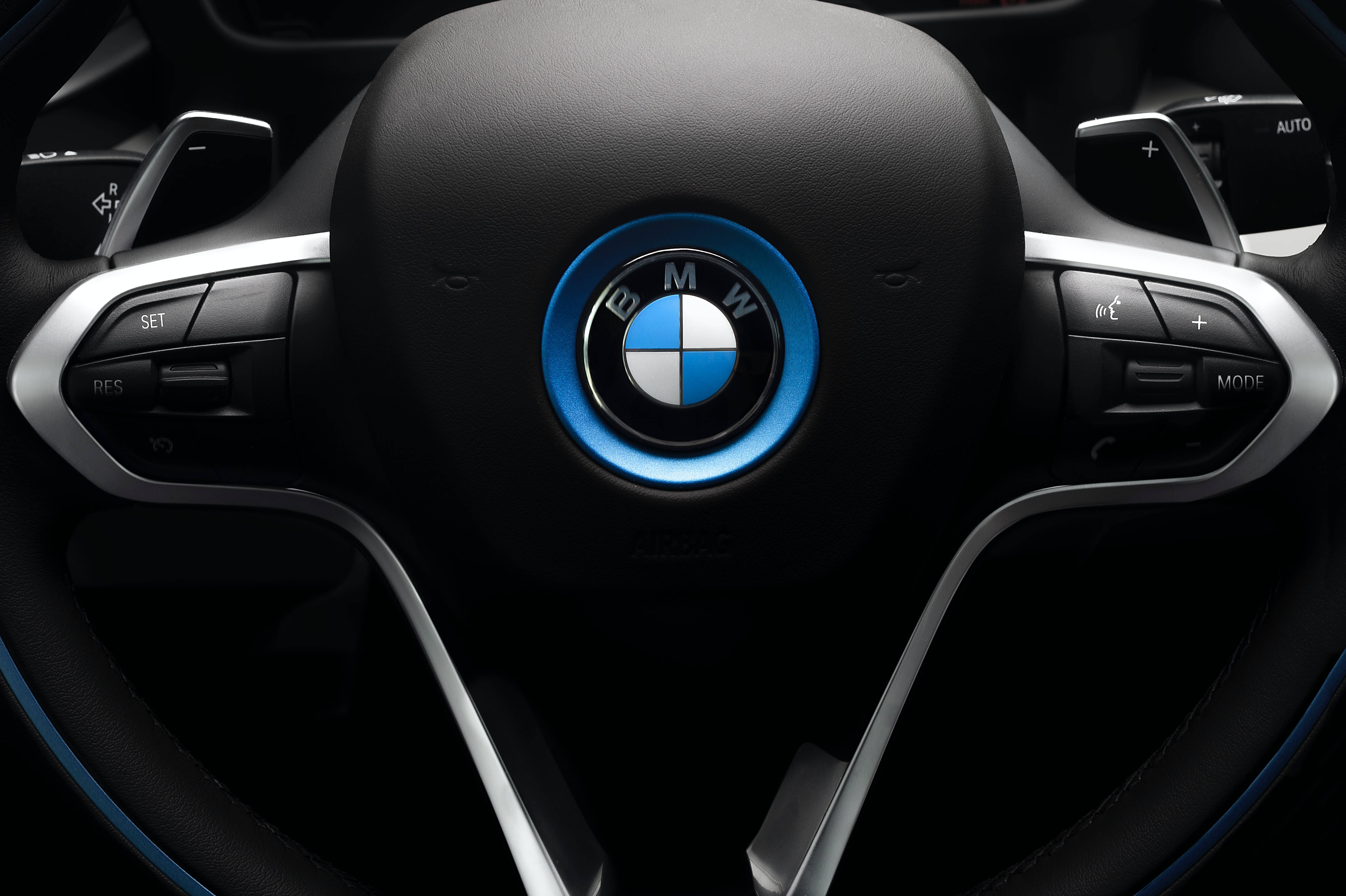 品牌 桌布 壁紙 — BMW i8 方向盤特寫，帶有發光藍色飾邊和皮革包裹，背景為深色內飾。