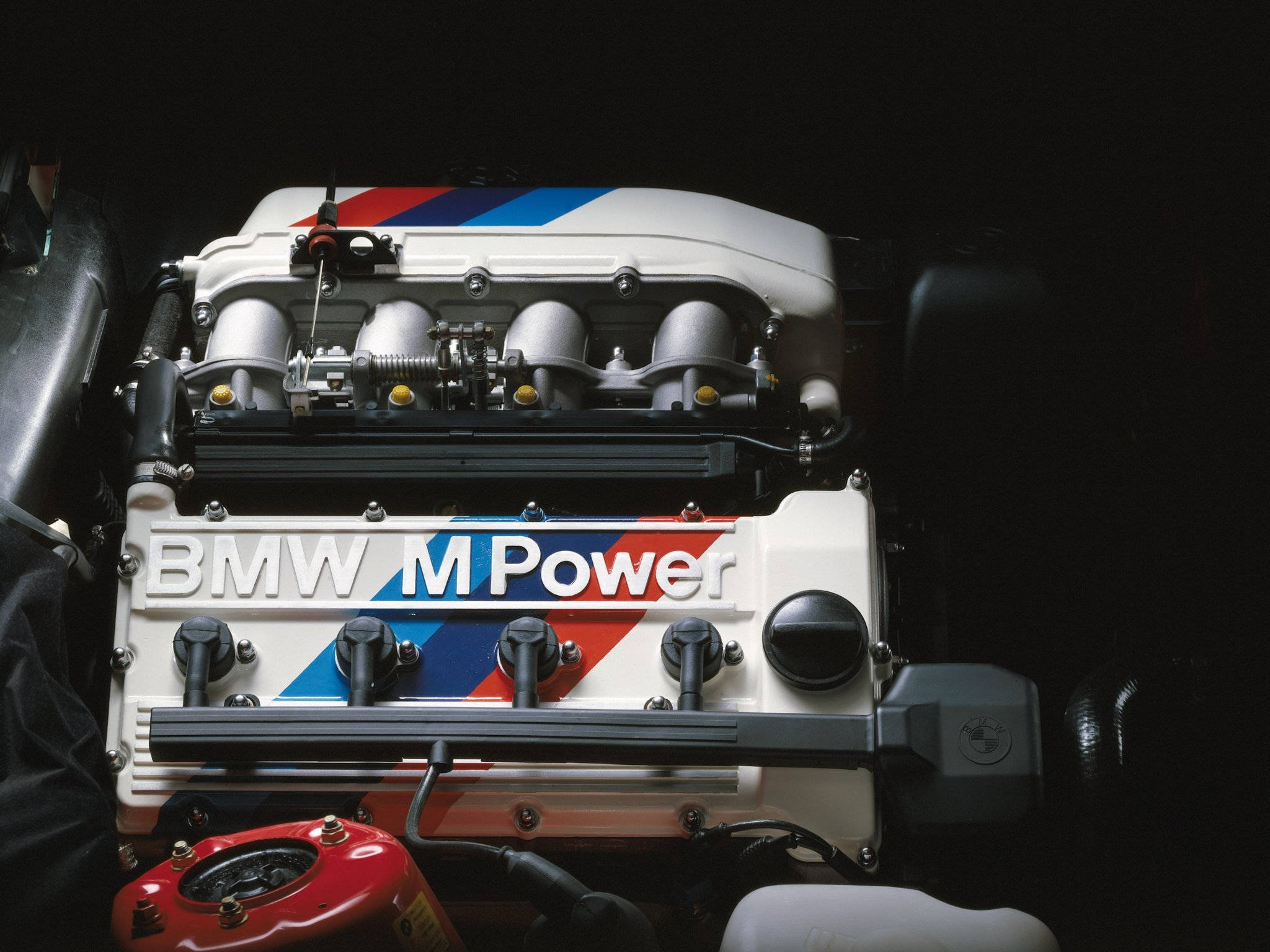 m 桌布 壁紙 — BMW M Power引擎特寫，帶有標誌性的藍、紅、白條紋，背景為深色。