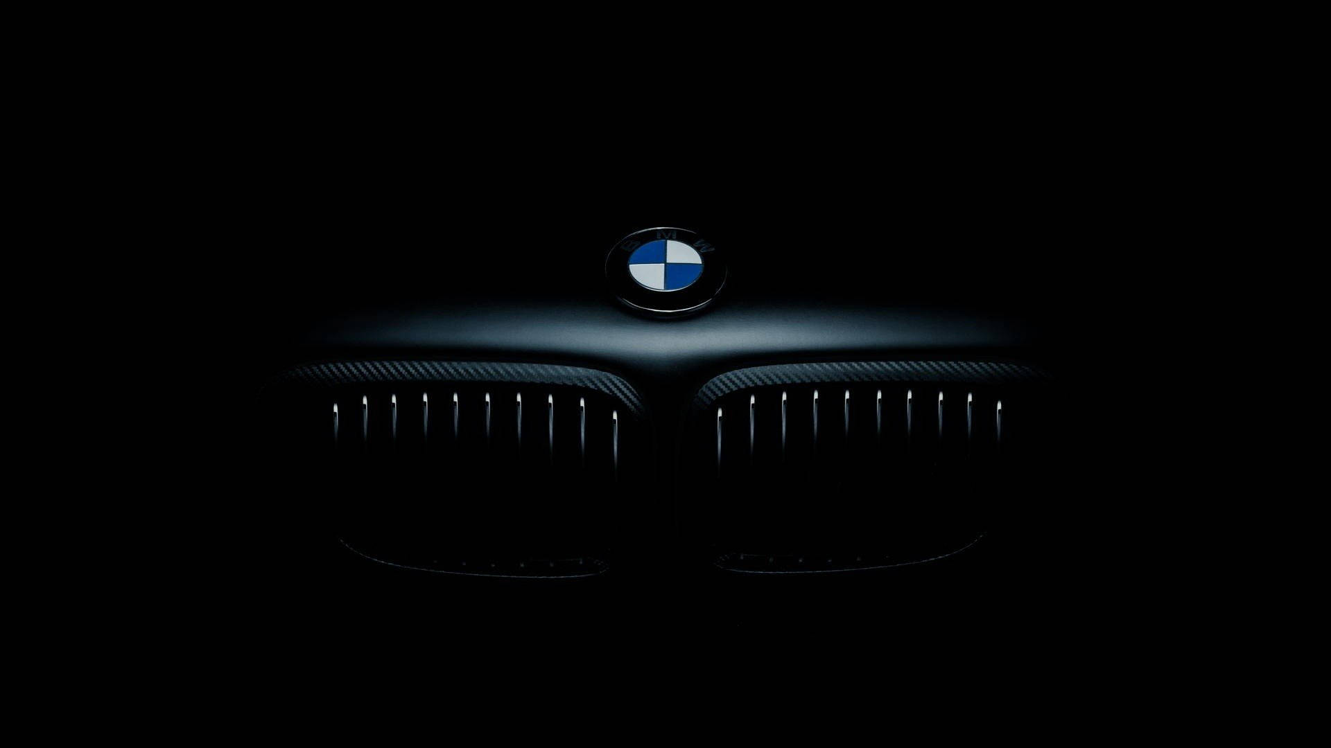 桌布 壁紙 — BMW 汽車格柵在漆黑中微微發光，上方標誌性圓形標誌亮起。