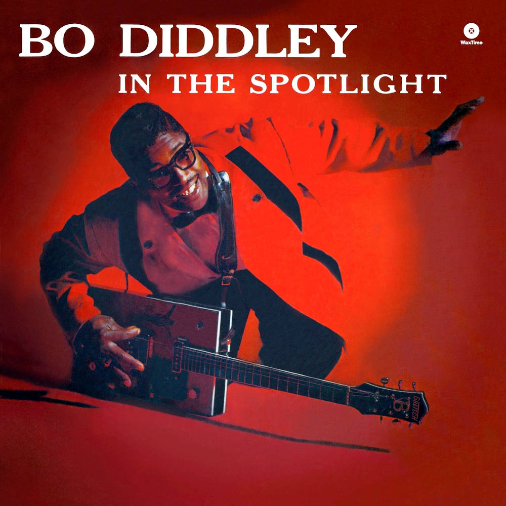 吉他動圖 桌布 壁紙 — Bo Diddley 在戲劇性的紅色聚光燈下，一邊彈奏他的標誌性電吉他，一邊充滿活力地咧嘴笑。